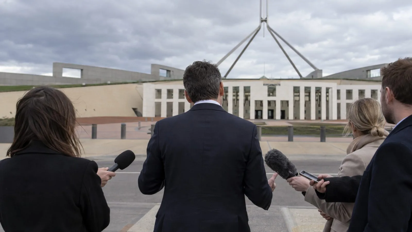 Journalists gather around microphones during a federal political briefing outside Parliament House in Canberra, Australia. (AI-generated image / EconoTimes)