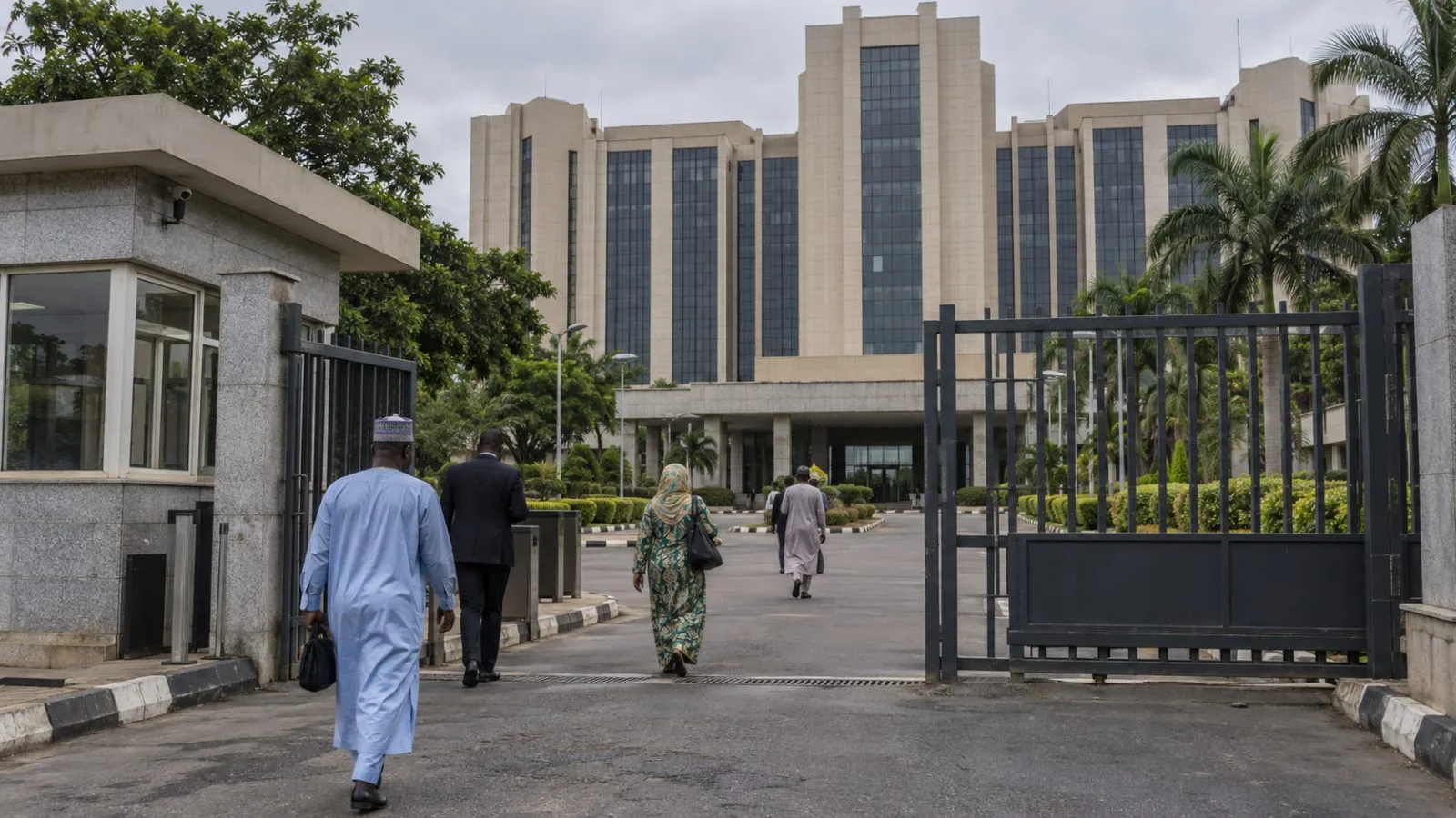Civil servants enter the Federal Ministry of Finance in Abuja, Nigeria, beneath an overcast morning sky. (AI-generated image / EconoTimes)