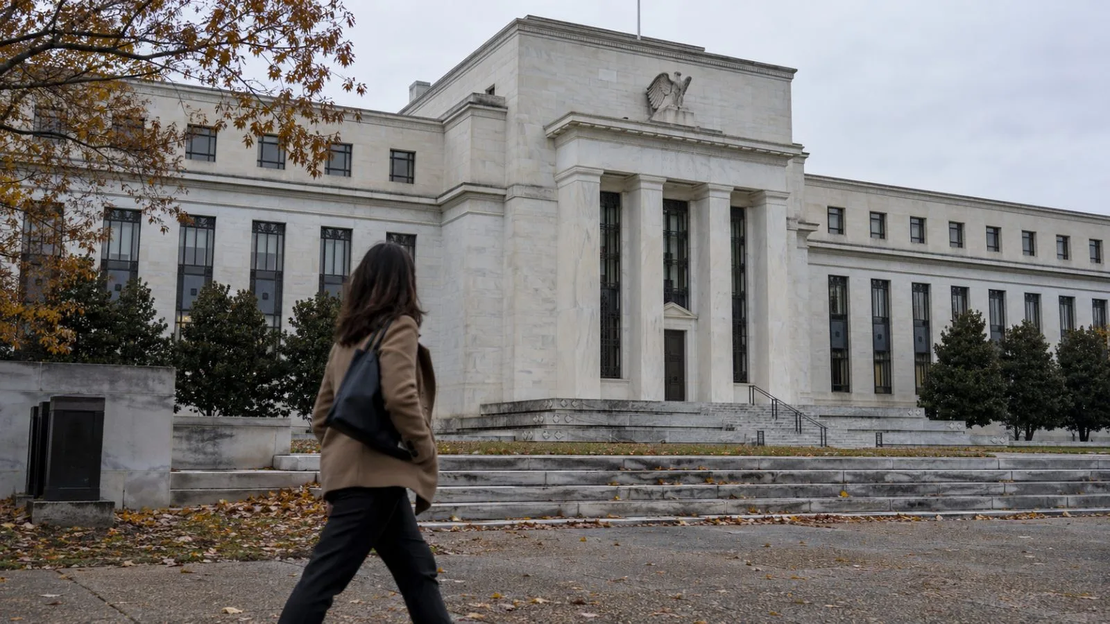 A pedestrian passes the Federal Reserve Board’s Eccles Building in Washington, D.C., beneath an overcast sky (AI-generated image / EconoTimes)