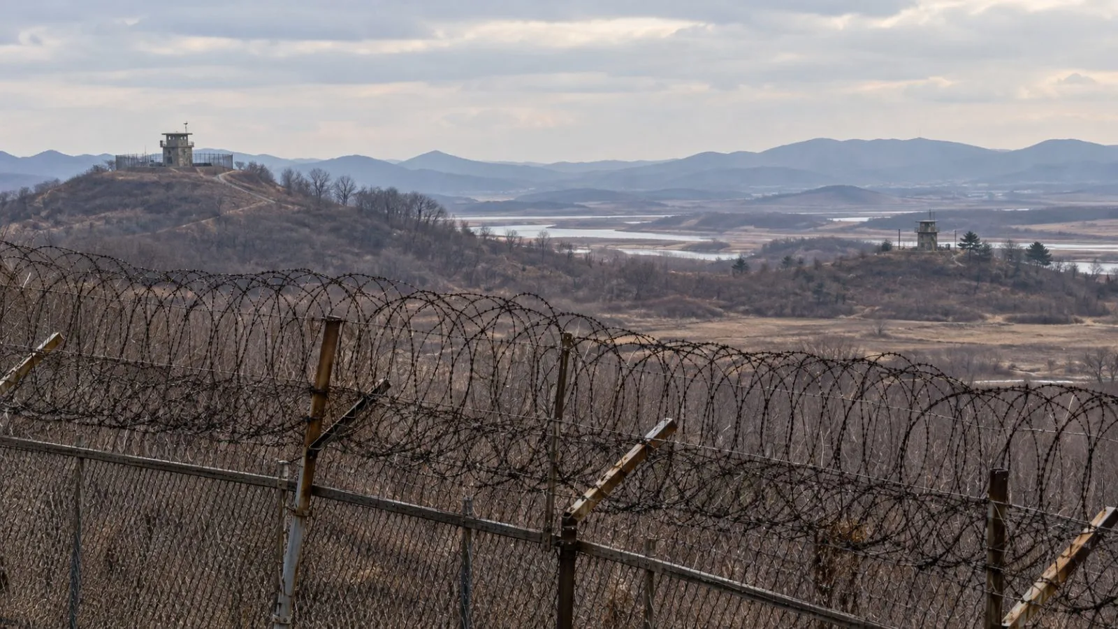Barbed-wire fences and distant guard posts overlook the border near Paju, South Korea. (AI-generated image / EconoTimes)