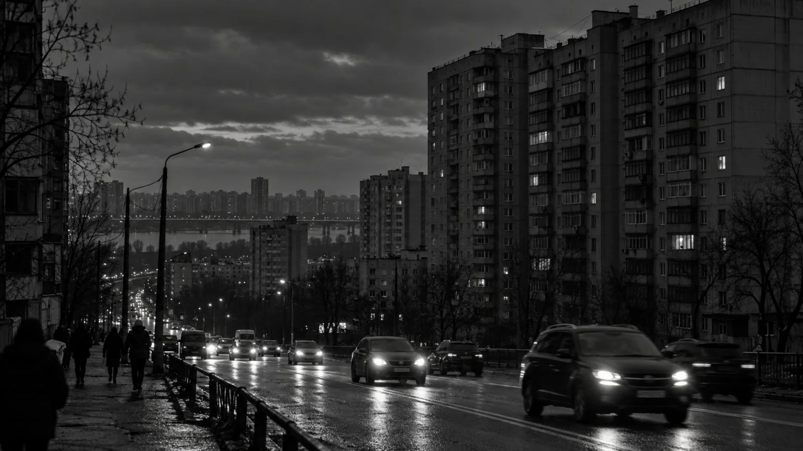 Cars pass mostly dark apartment blocks on a Kyiv street during an evening power outage (AI-generated image / EconoTimes)