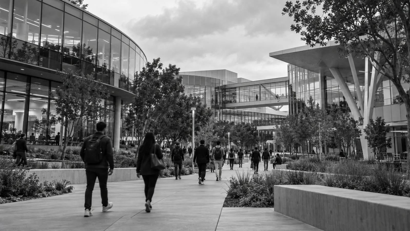 Employees cross a campus walkway beside glass office buildings in Mountain View, California. / EconoTimes.ai (mono)
