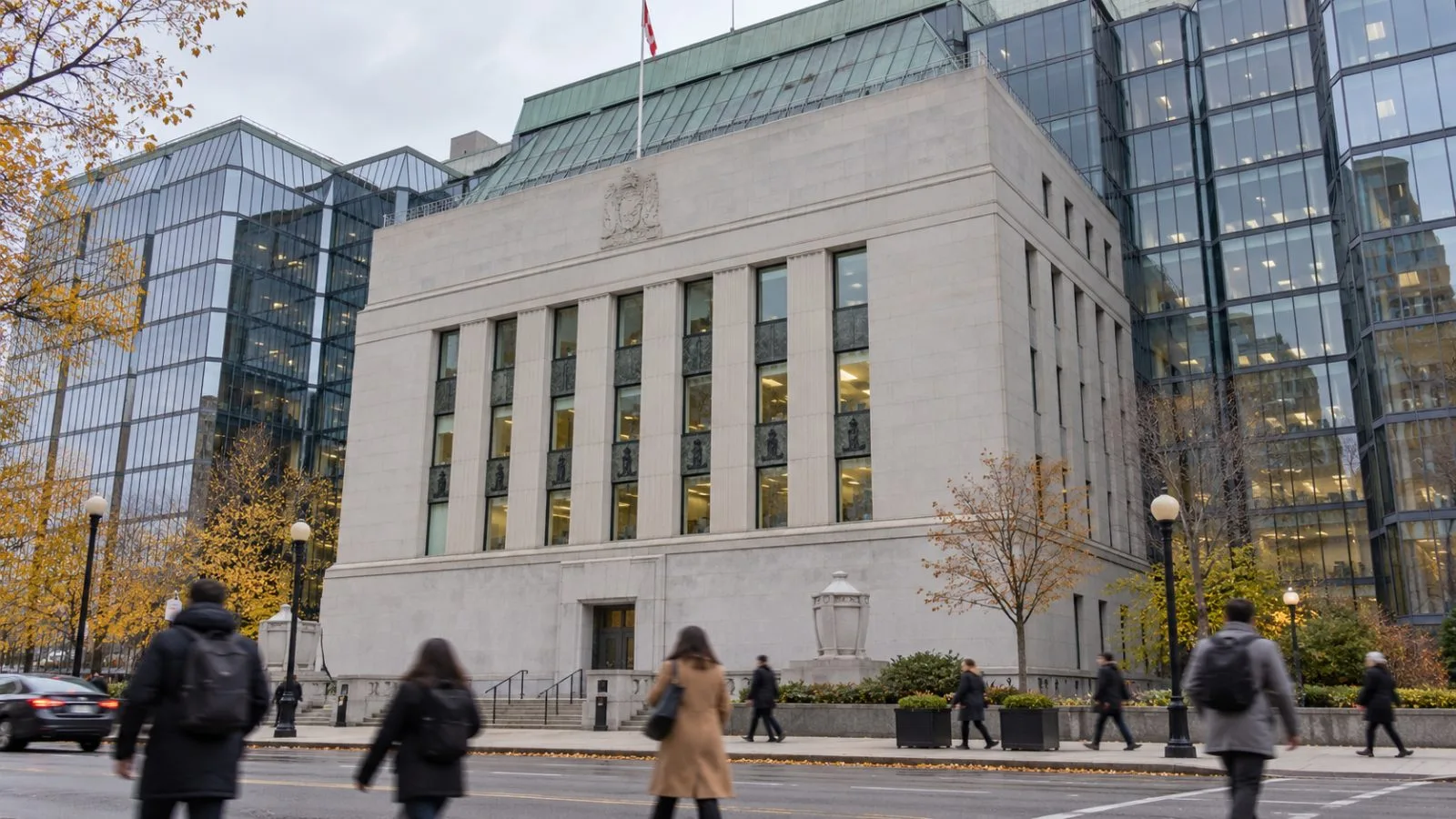 Pedestrians pass the Bank of Canada building in Ottawa on an overcast morning. / EconoTimes.ai