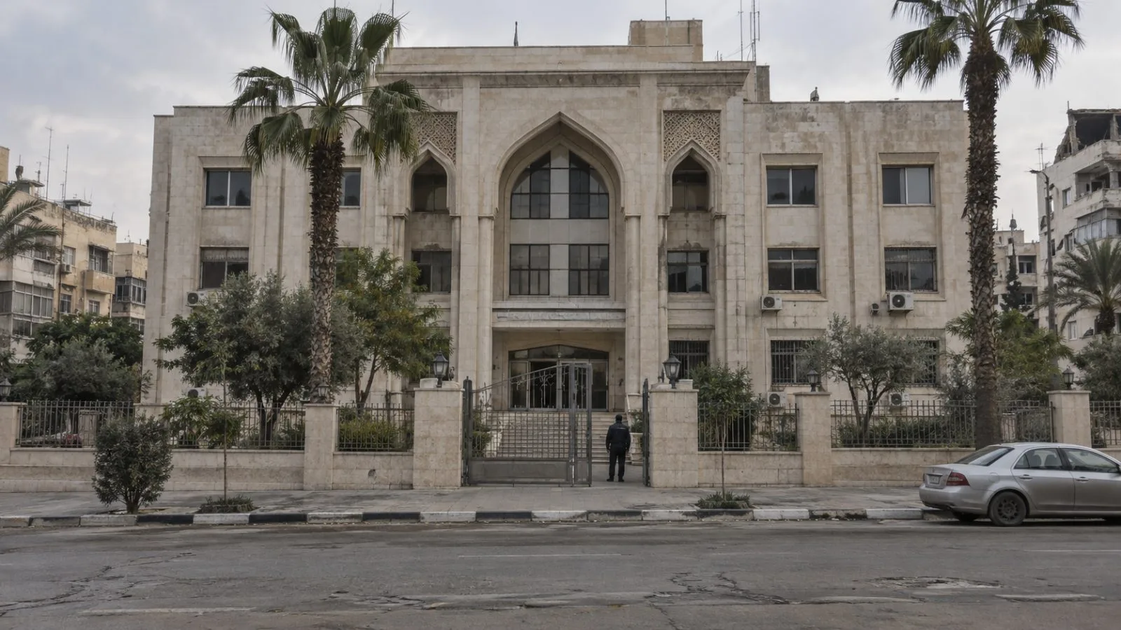 An anonymous guard stands at the entrance of a municipal building in Gaza City, Gaza Strip. (AI-generated image / EconoTimes)