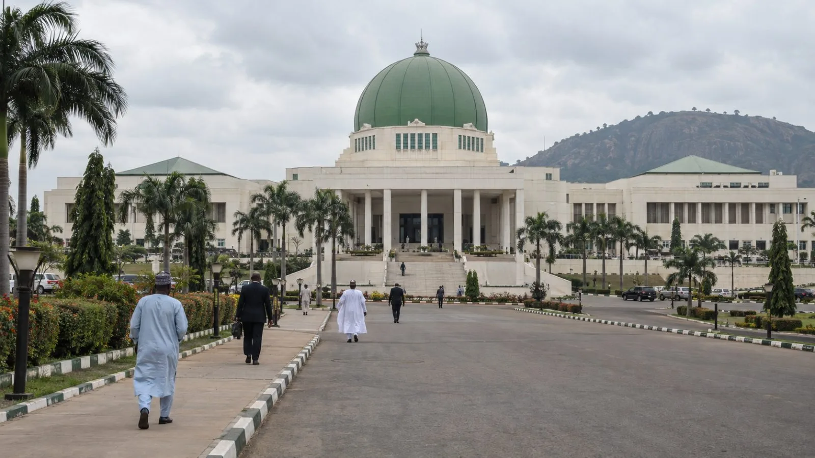 Pedestrians approach Nigeria’s National Assembly complex in Abuja on an overcast morning. (AI-generated image / EconoTimes)
