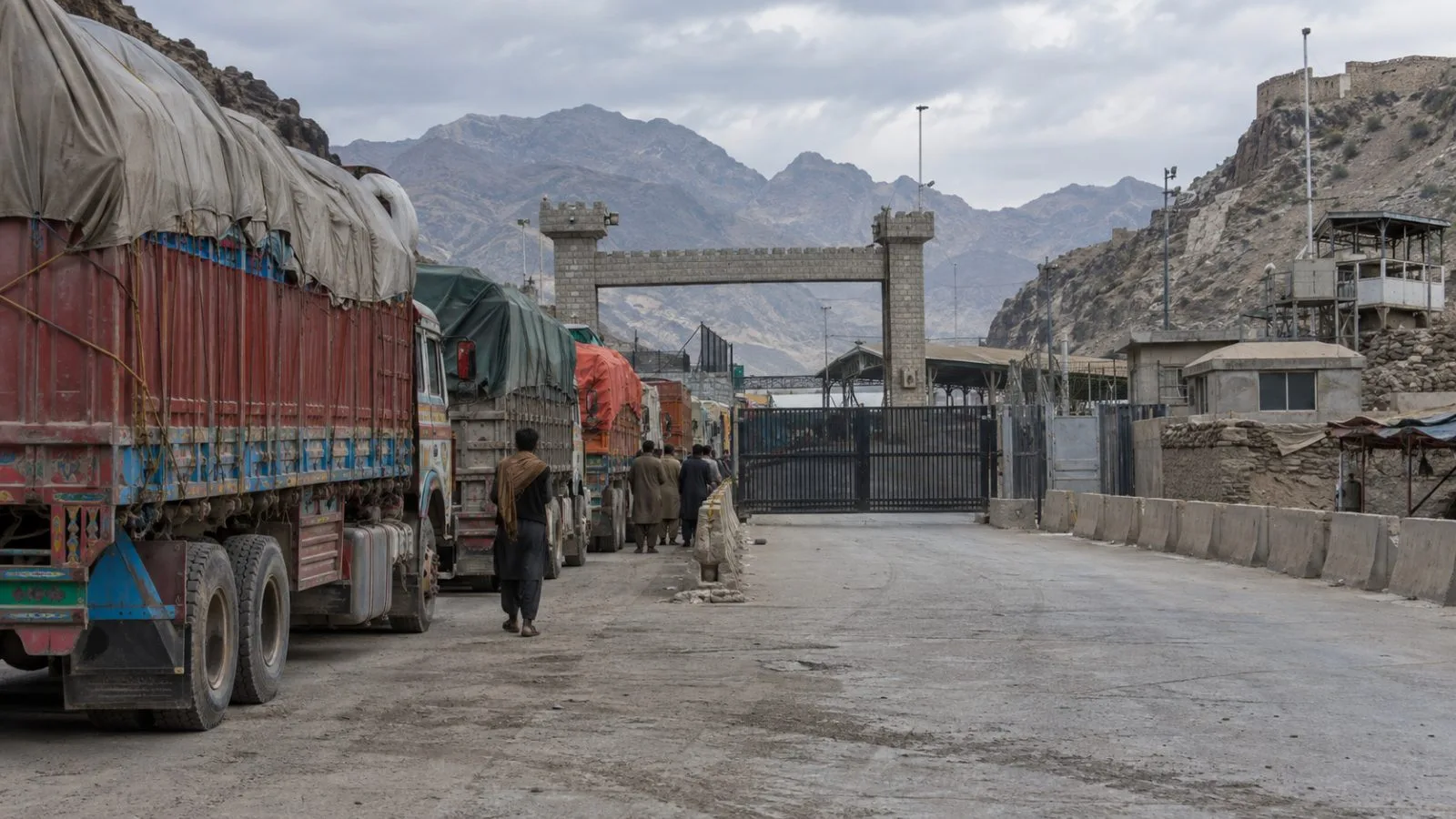 Freight trucks wait near the Torkham border crossing in eastern Afghanistan (AI-generated image / EconoTimes)