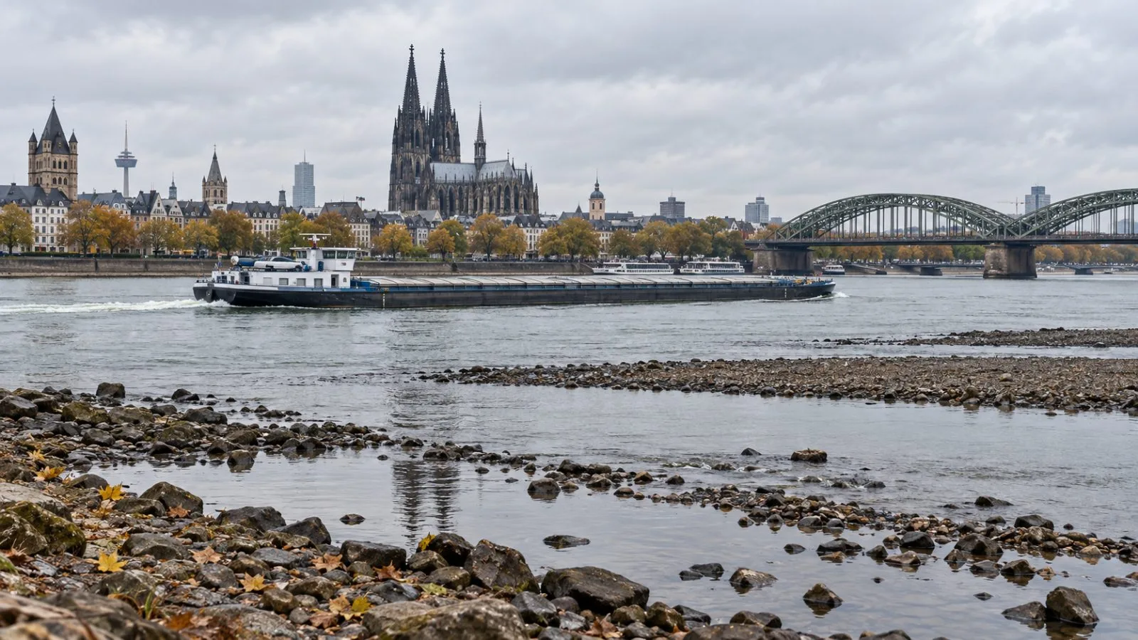 A cargo barge passes exposed riverbank stones on the Rhine in Cologne, Germany. / EconoTimes.ai