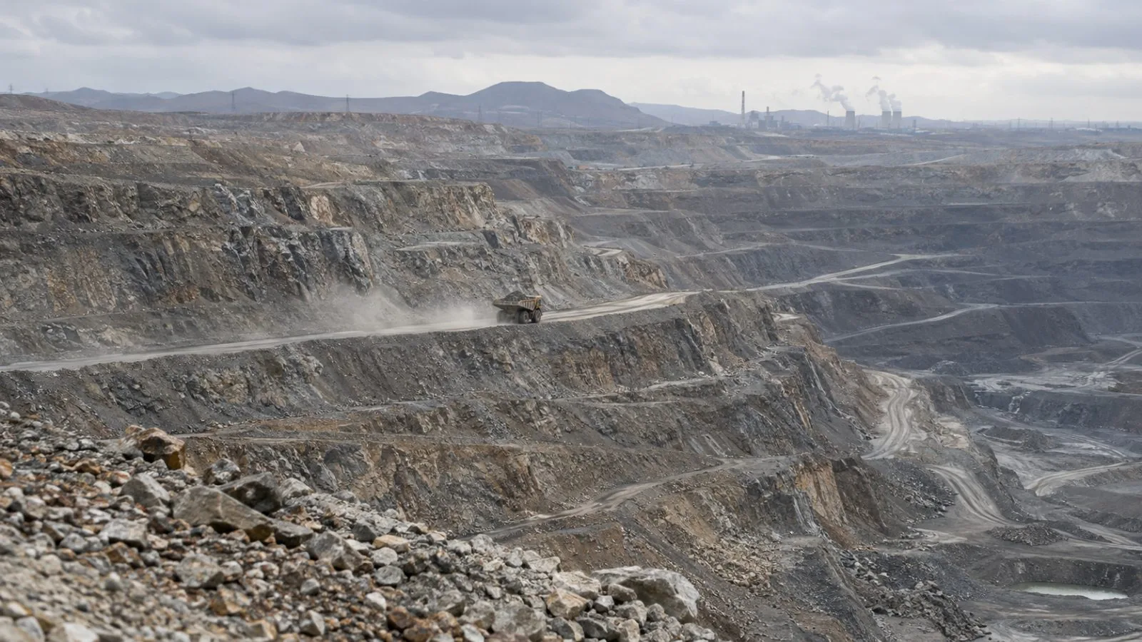 A haul truck moves along a terraced bench at the Bayan Obo mine near Baotou, China. (AI-generated image / EconoTimes)