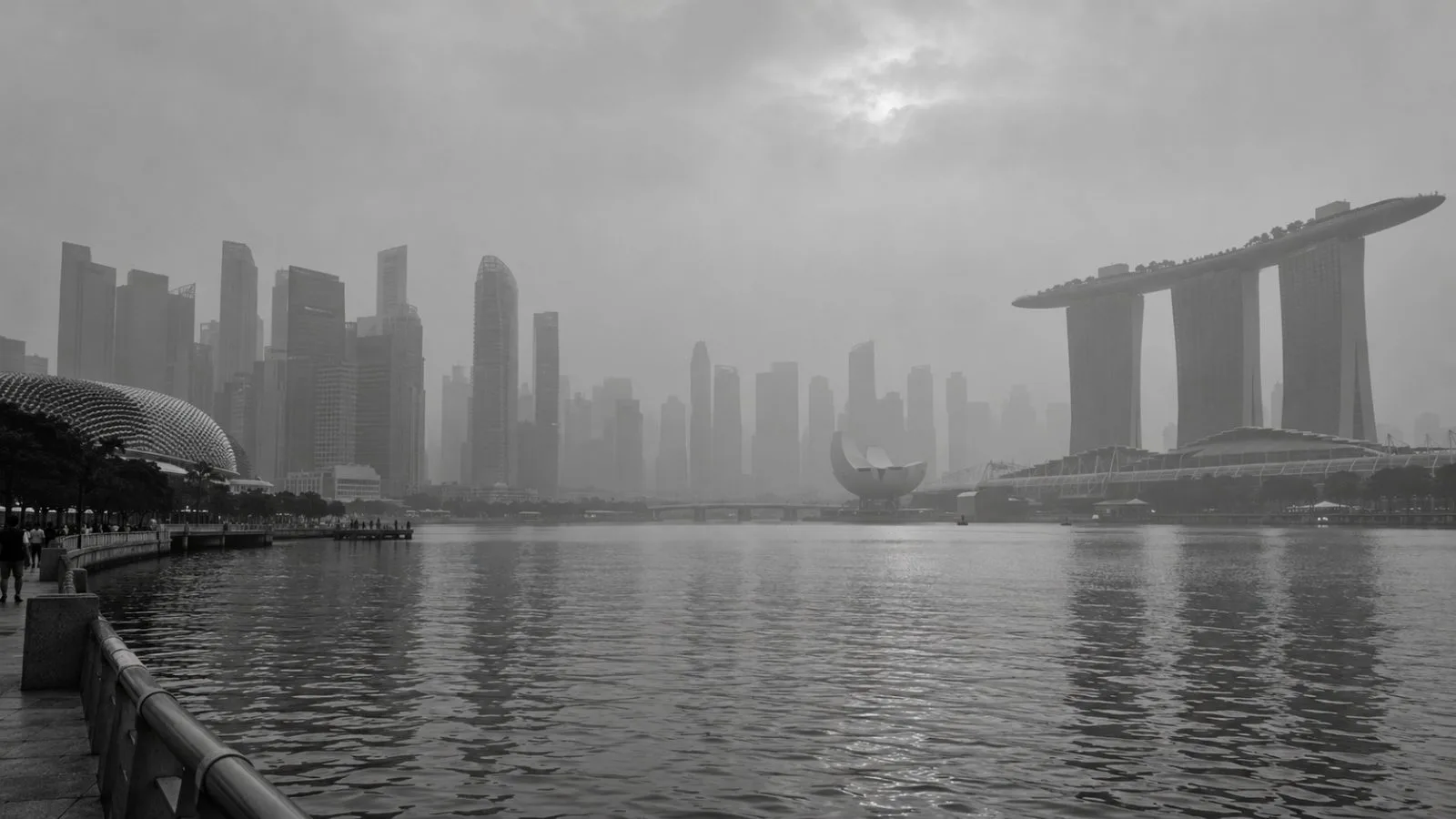 Haze softens the skyline above Singapore’s Marina Bay as pedestrians pass. / EconoTimes.ai (mono)