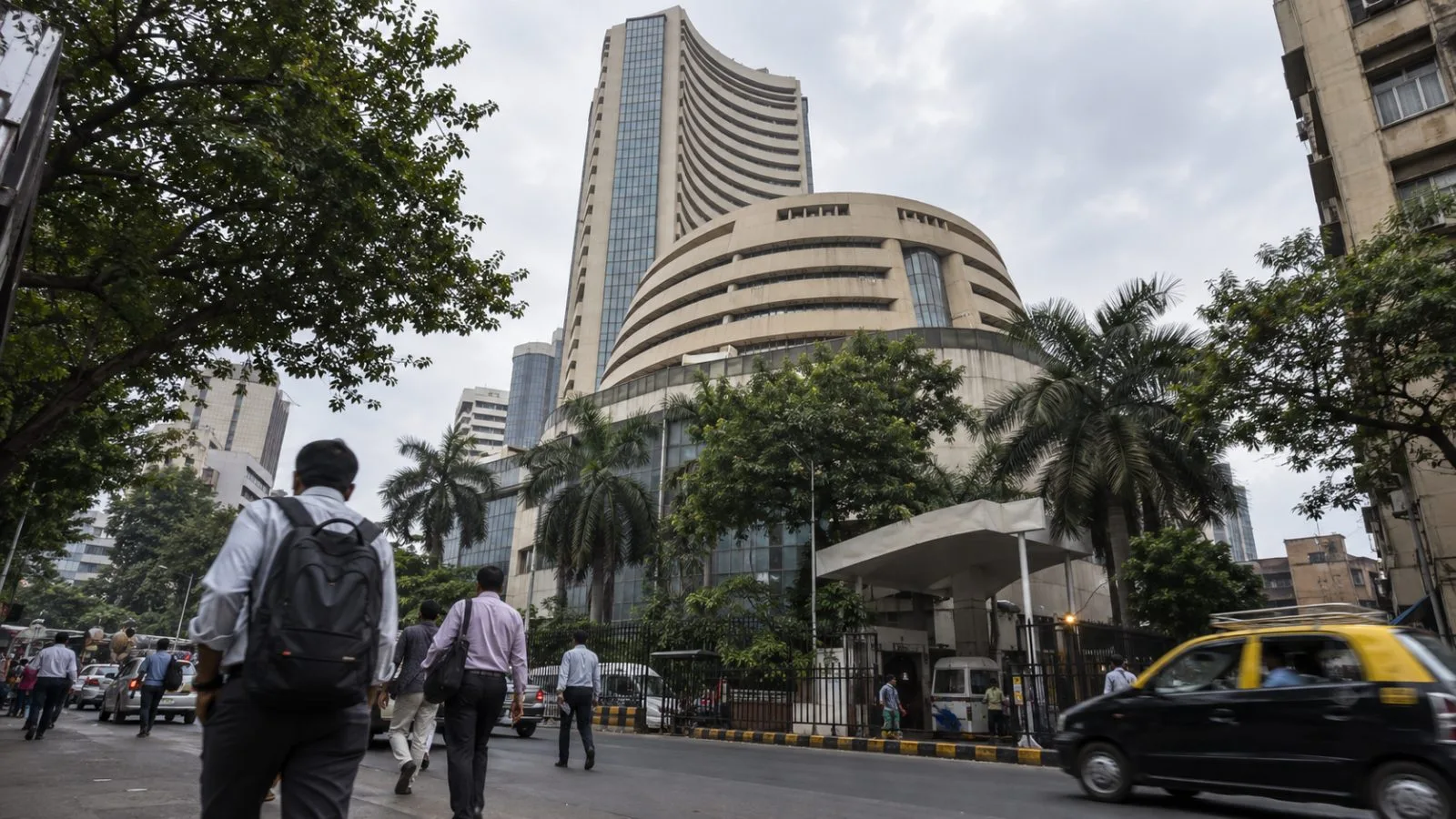 Pedestrians pass the Bombay Stock Exchange building in Mumbai on an overcast afternoon. (AI-generated image / EconoTimes)