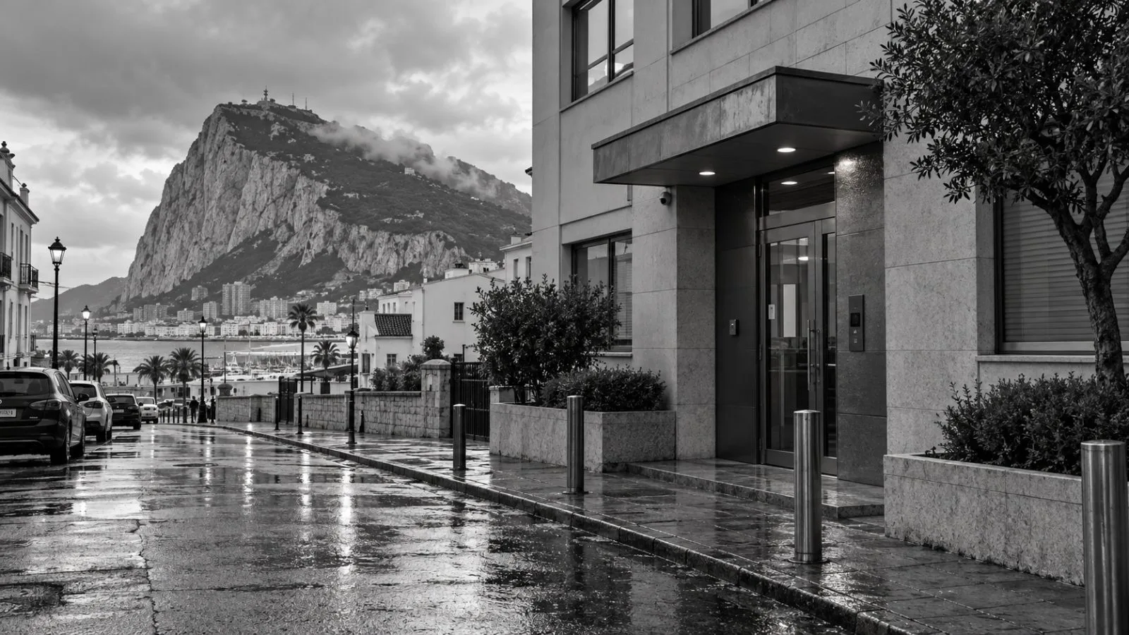 A glass office entrance sits on a narrow street beneath Gibraltar's Rock. / EconoTimes.ai