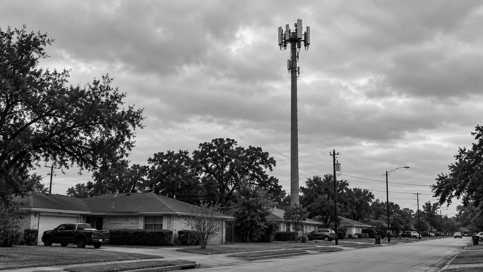 A cellular tower rises above a Houston neighborhood beneath an overcast Texas sky. / EconoTimes.ai