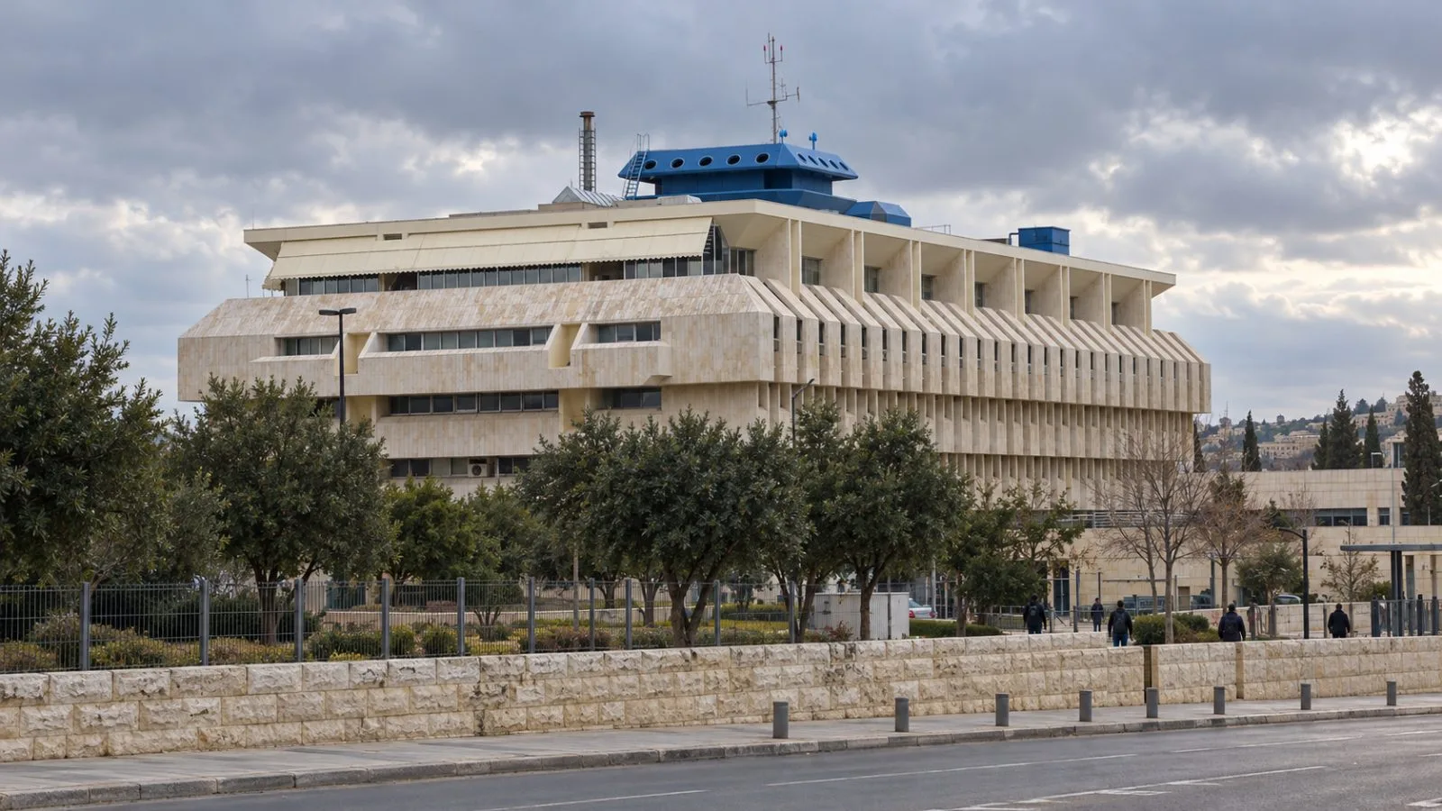 Pedestrians pass the Bank of Israel headquarters in Jerusalem under overcast skies. / EconoTimes.ai