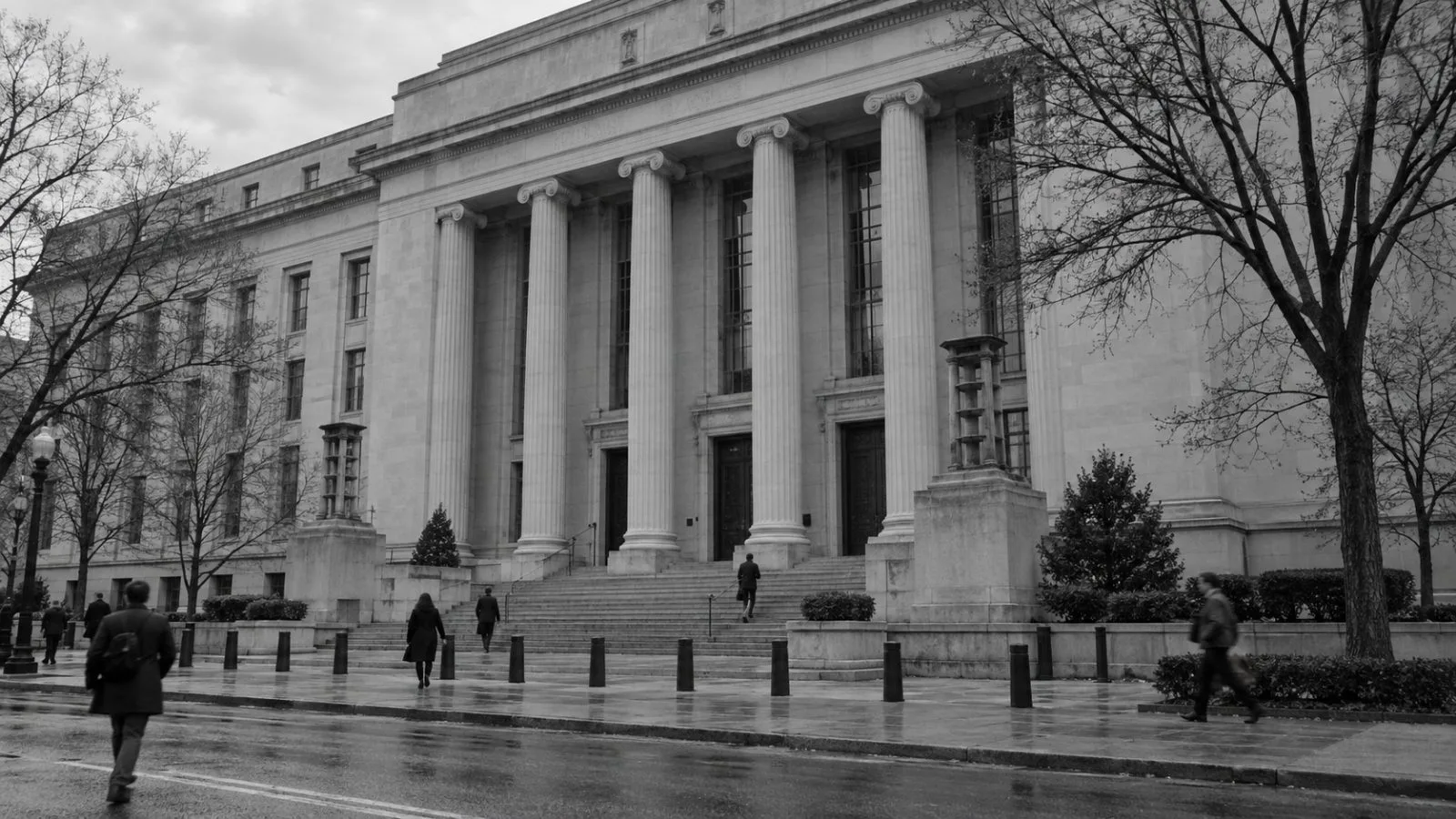 Pedestrians pass the Justice Department headquarters in Washington on an overcast morning. / EconoTimes.ai (mono)