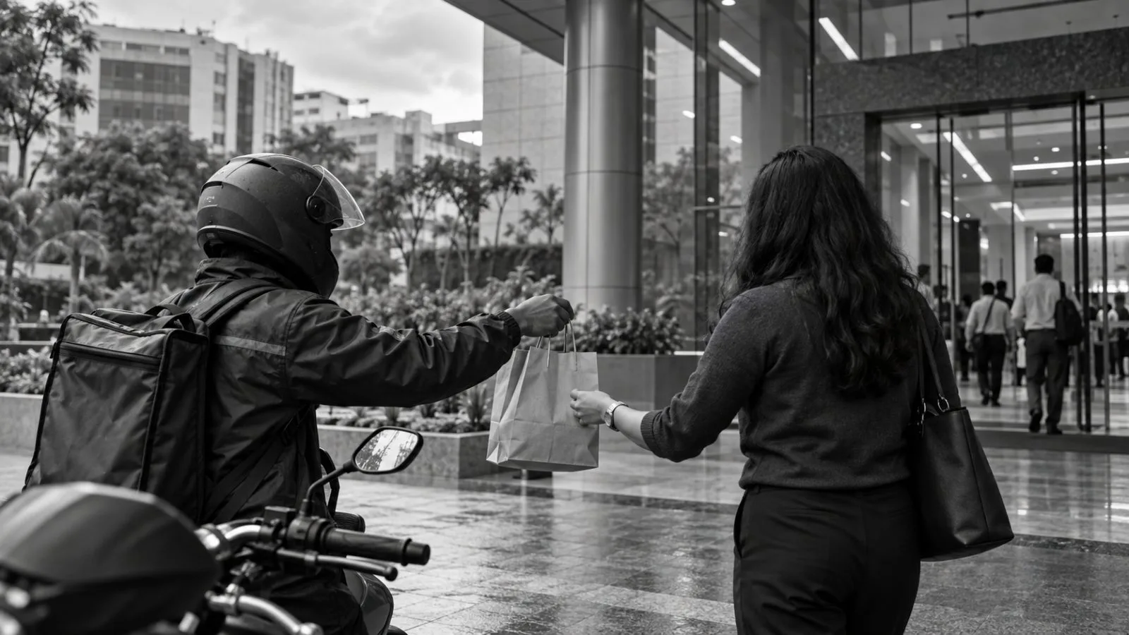 A delivery rider hands a takeaway meal to an office worker in Bengaluru. / EconoTimes.ai