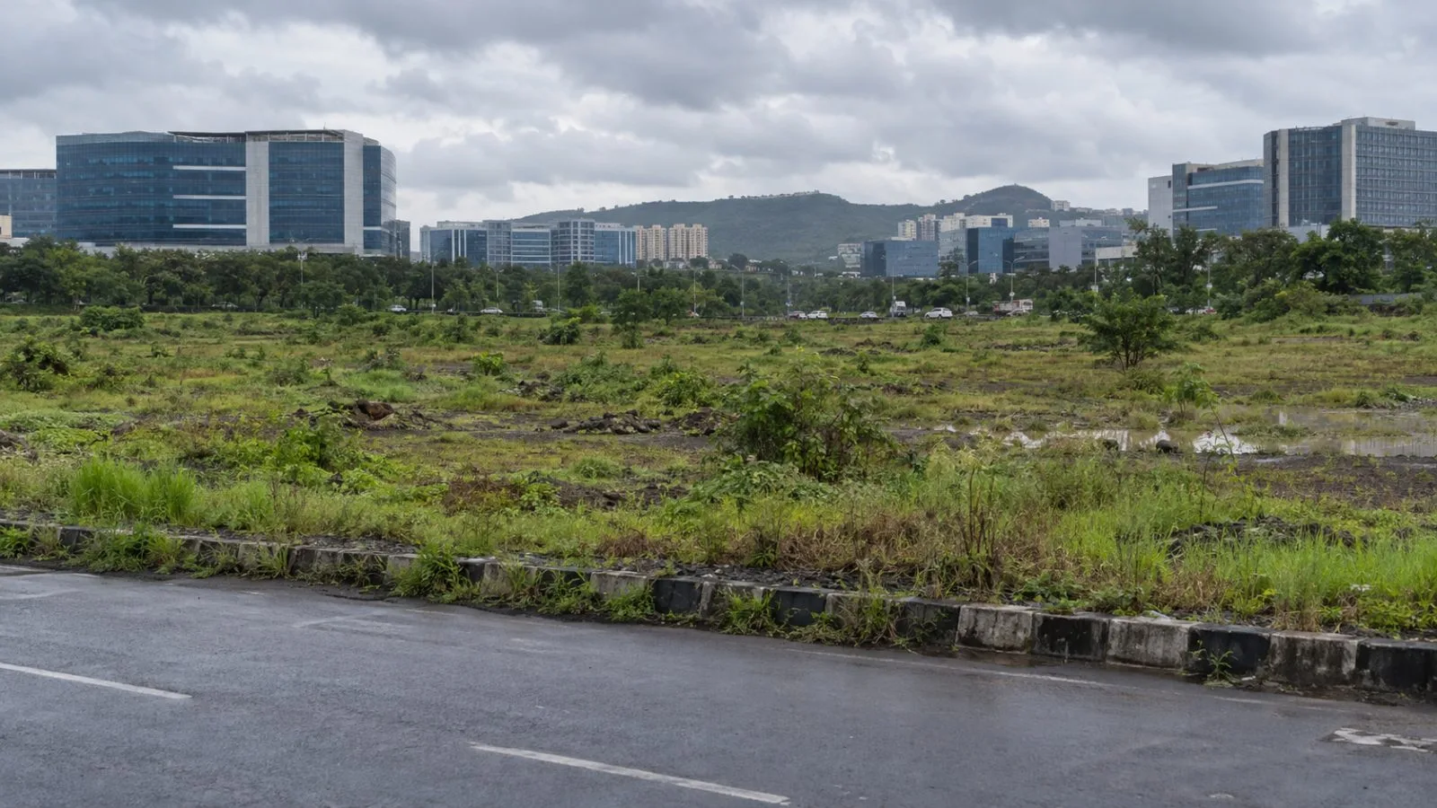 An open development parcel sits beside office buildings in Hinjewadi, Pune. (AI-generated image / EconoTimes)