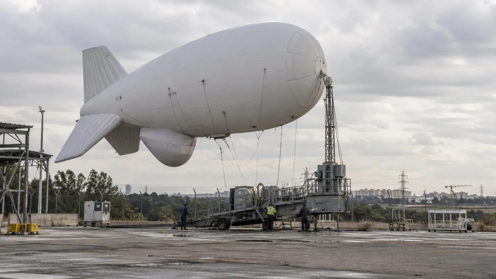A tethered surveillance aerostat stands above its mooring trailer in Yavne, Israel (AI-generated image / EconoTimes)