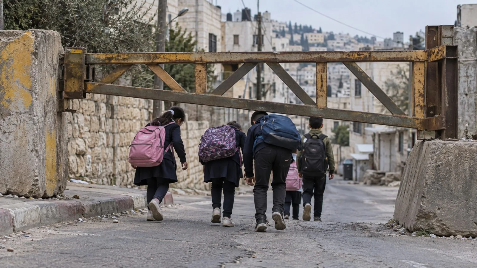 Palestinian pupils pass beneath a military road gate on a school route in Jenin, West Bank. (AI-generated image / EconoTimes)