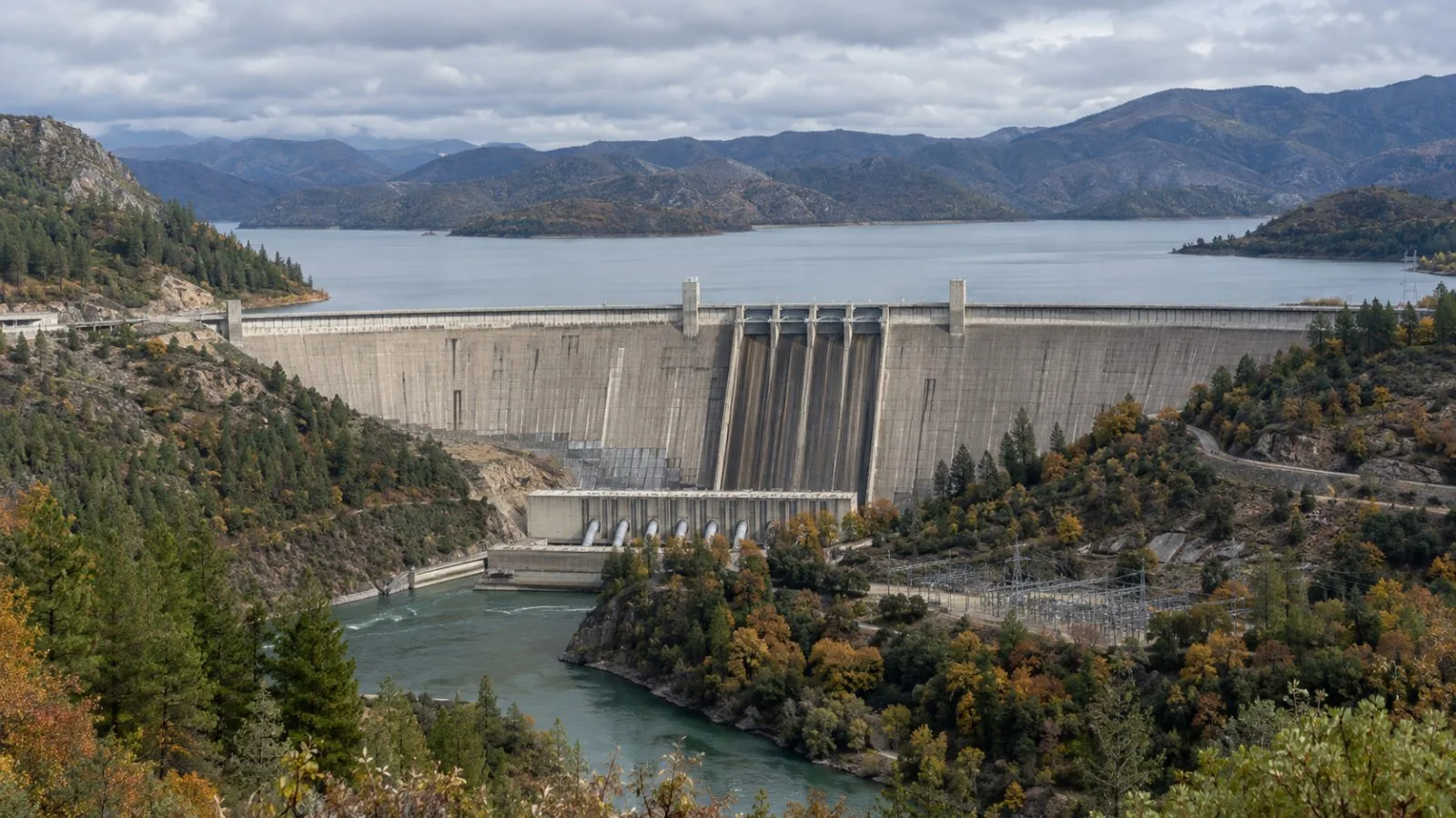 Shasta Dam spans the Sacramento River near Redding, California, beneath an overcast autumn sky. (AI-generated image / EconoTimes)