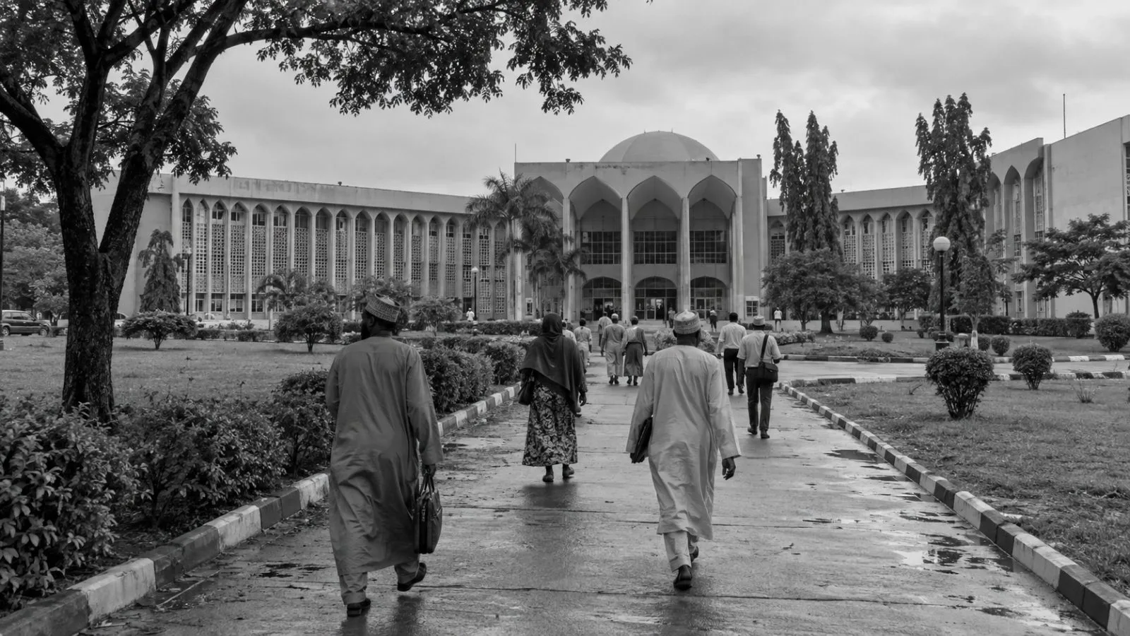 Staff walk toward an administrative building at Ahmadu Bello University in Zaria. (AI-generated image / EconoTimes)