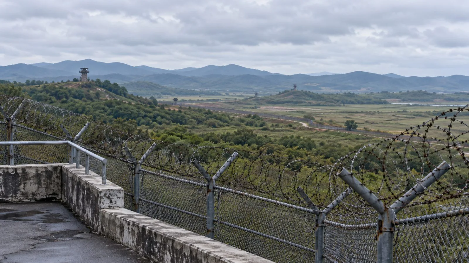 Barbed-wire fencing frames distant guard posts near the Demilitarized Zone in Paju, South Korea. (AI-generated image / EconoTimes)