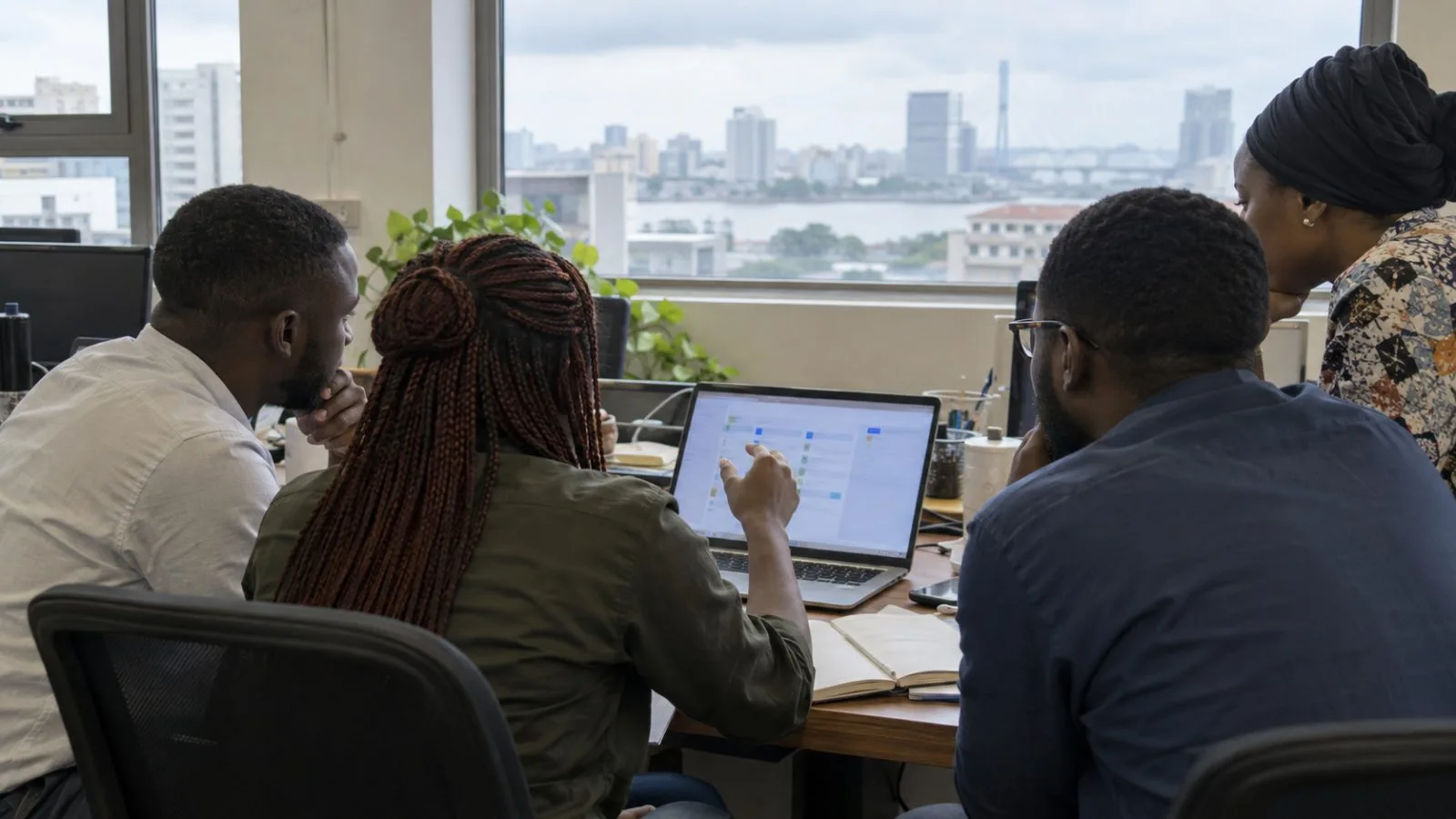 A small product team reviews a laptop in a Lagos office. (AI-generated image / EconoTimes)