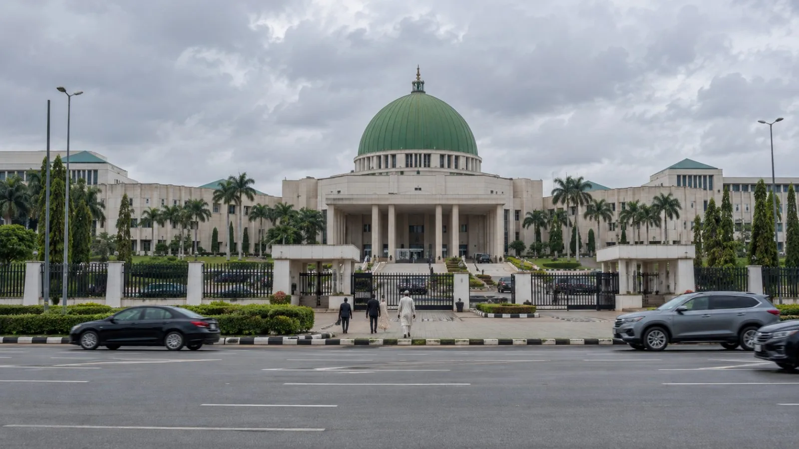 Pedestrians approach Nigeria’s National Assembly complex in Abuja on an overcast morning (AI-generated image / EconoTimes)