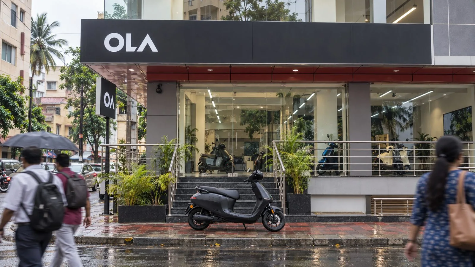 An electric scooter stands outside a Bengaluru showroom as pedestrians pass on the wet pavement. / EconoTimes.ai