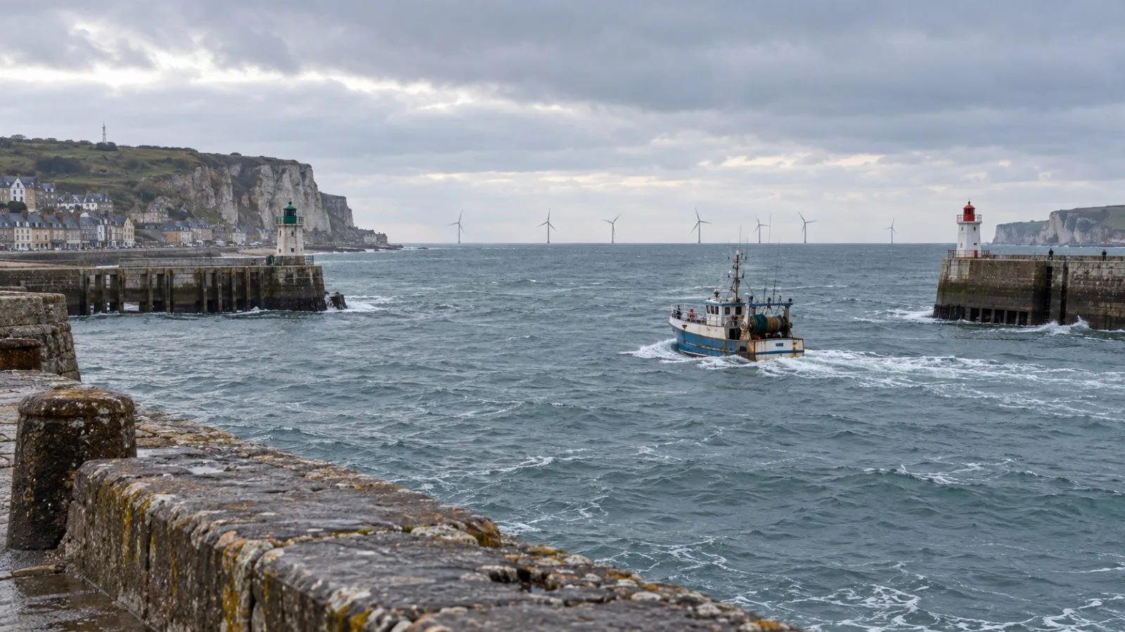 Offshore turbines rise beyond Fécamp’s harbor in Normandy, France, beneath a gray afternoon sky. / EconoTimes.ai