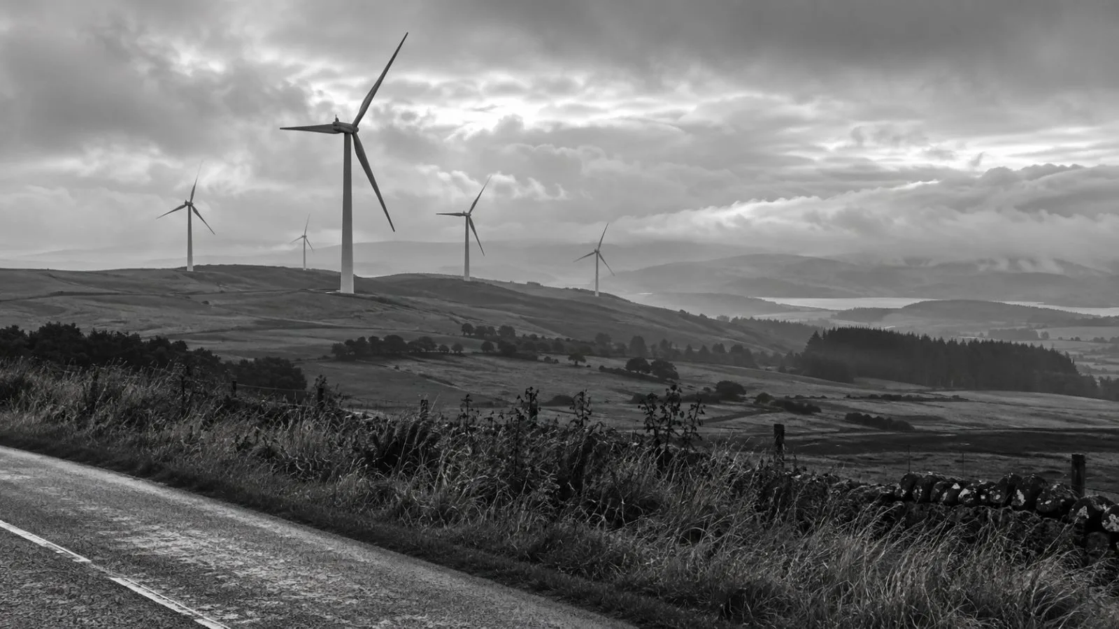 Wind turbines turn above a green ridge near Glasgow, Scotland, beneath an overcast sky. (AI-generated image / EconoTimes)