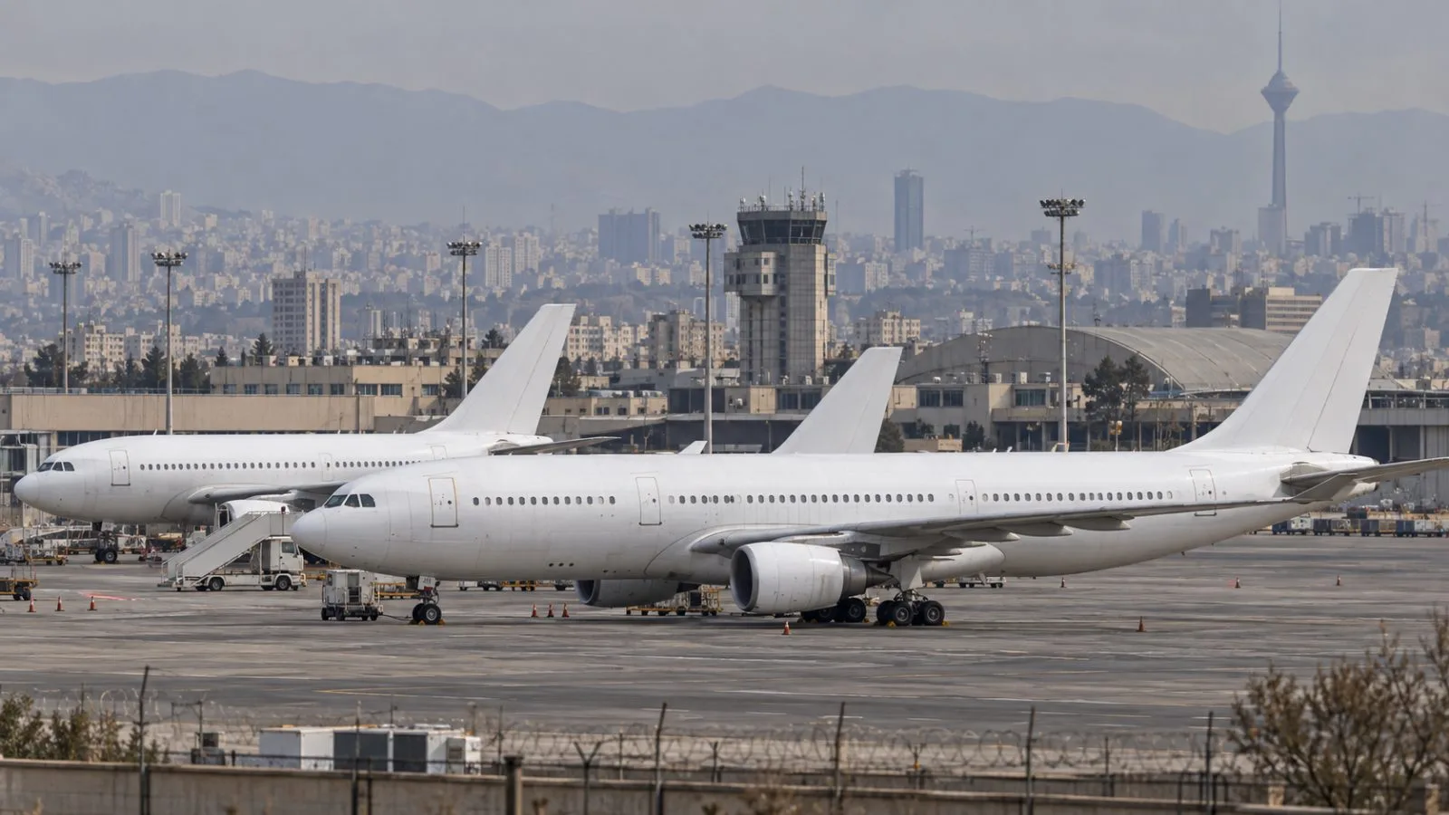 Passenger aircraft stand on the apron at Mehrabad International Airport in Tehran. / EconoTimes.ai