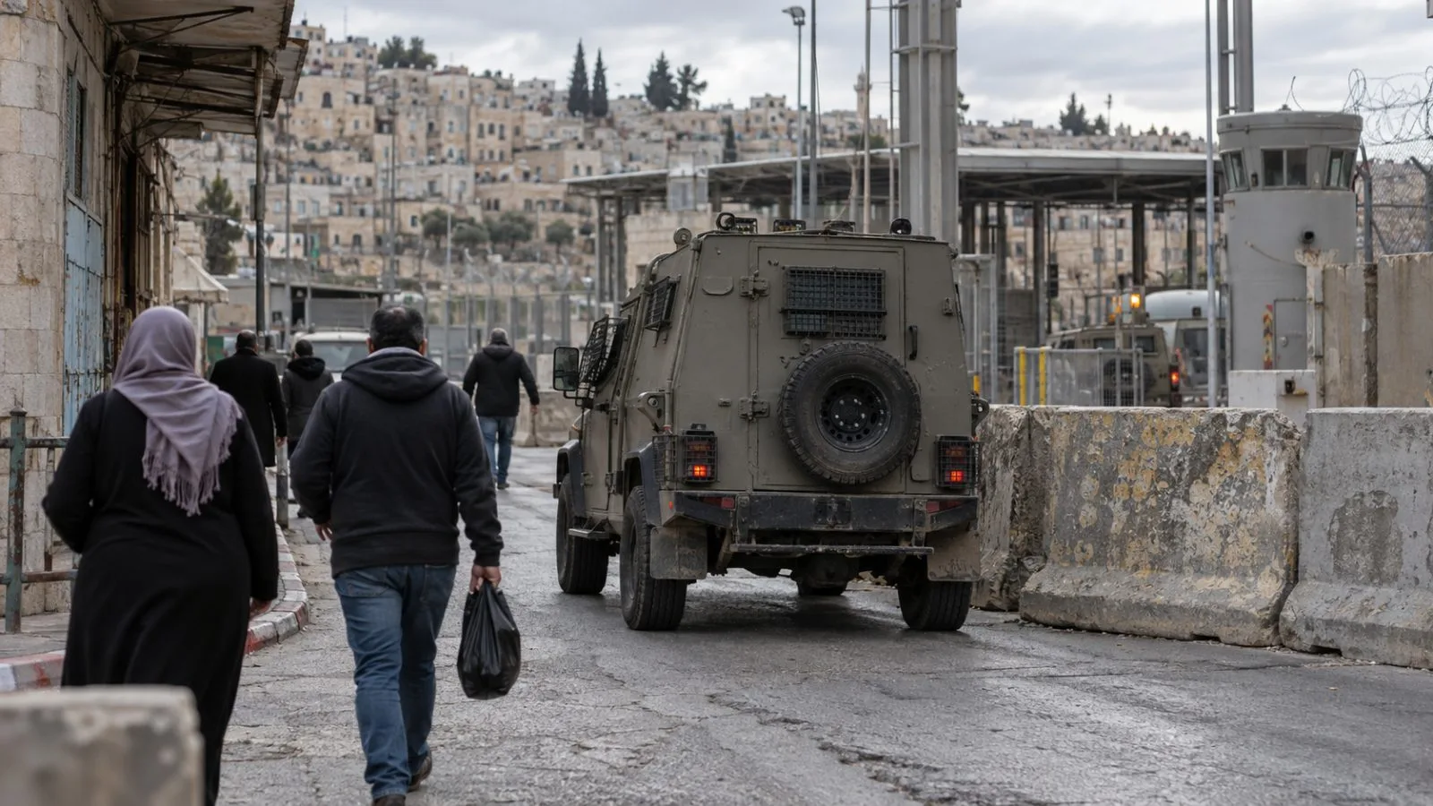 A military vehicle passes a concrete barrier on a street in Hebron, West Bank (AI-generated image / EconoTimes)