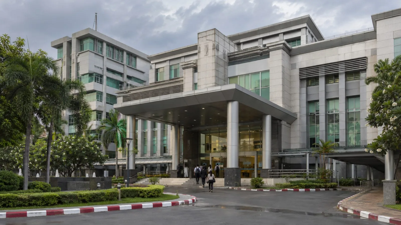 Visitors enter Thailand’s Department of Intellectual Property in Nonthaburi under cloudy skies. (AI-generated image / EconoTimes)