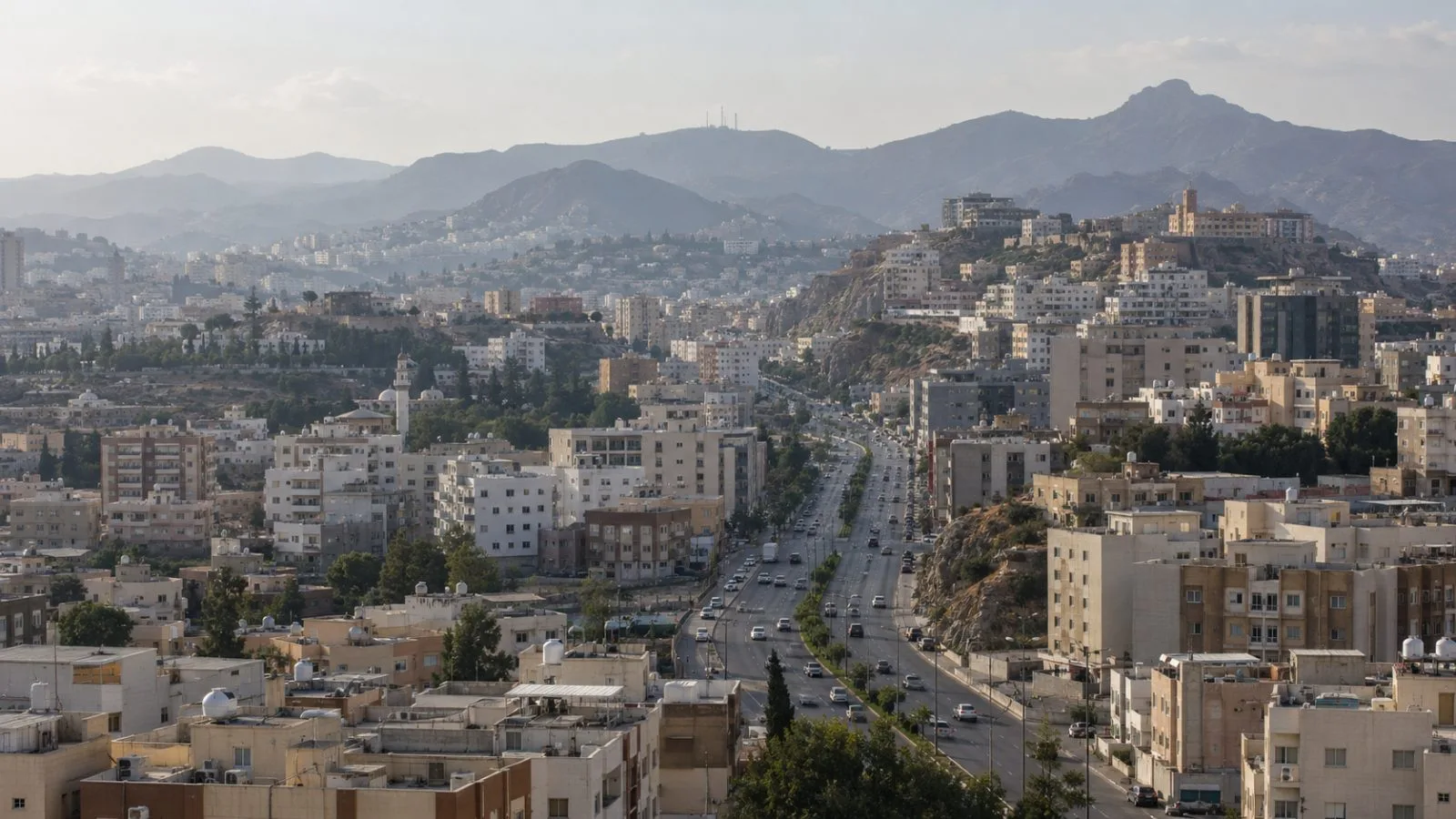 Traffic moves along a main street in Abha, Saudi Arabia, with the highlands beyond. (AI-generated image / EconoTimes)