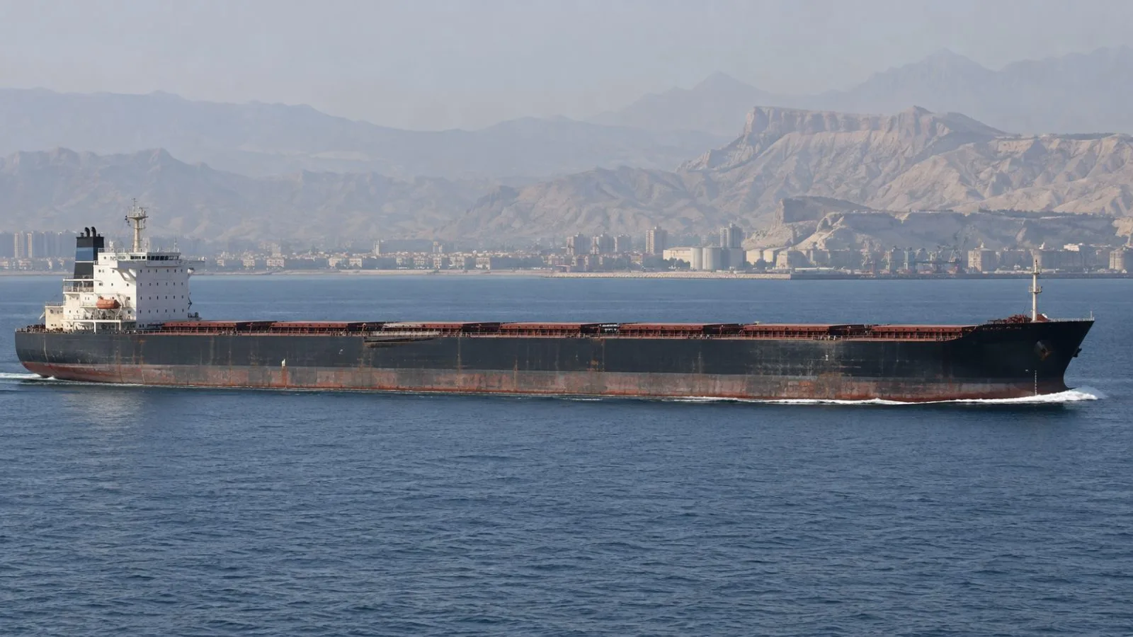 A bulk carrier passes near Bandar Abbas along Iran’s Strait of Hormuz coast (AI-generated image / EconoTimes)