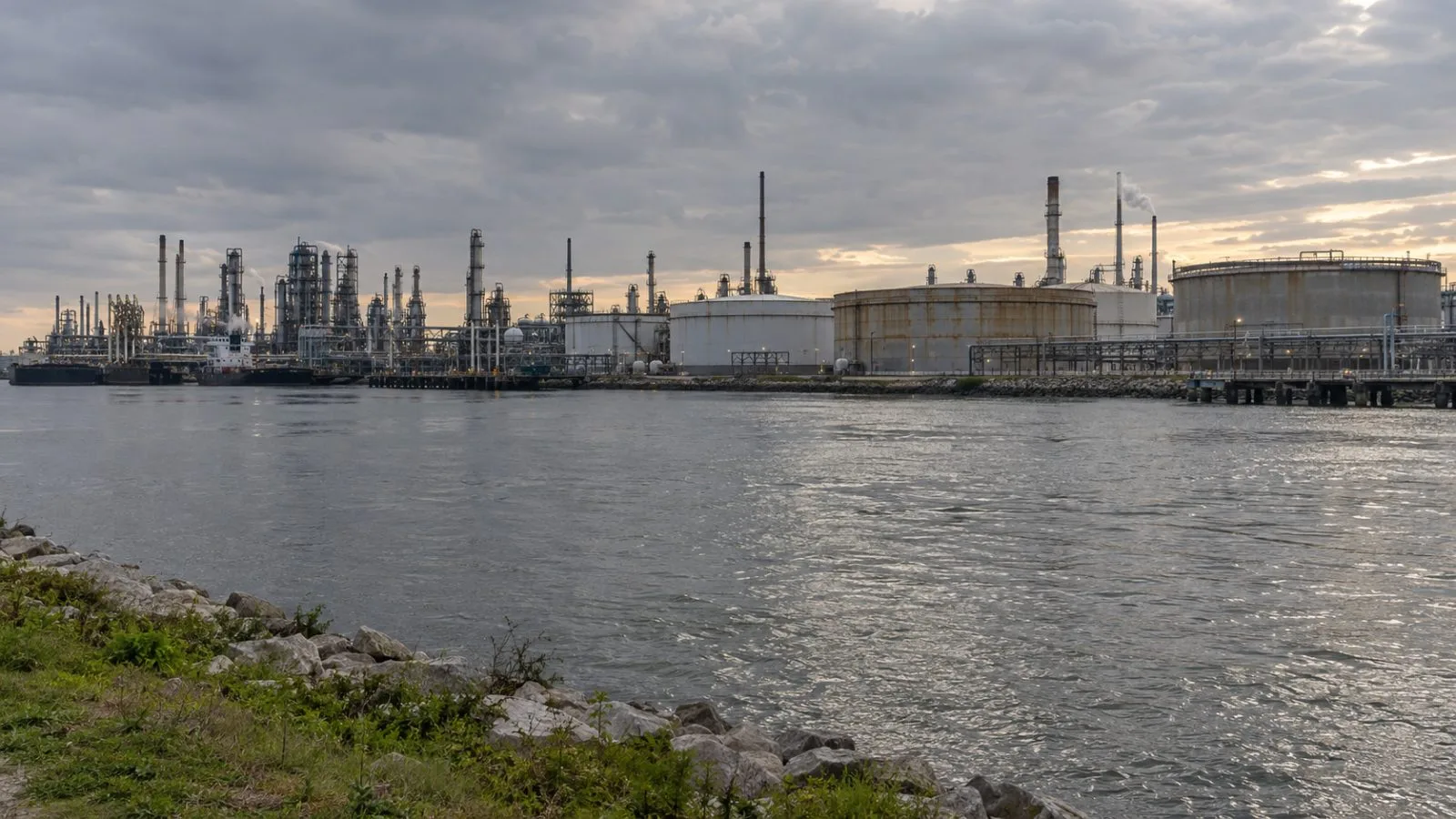 Oil storage tanks line the Houston Ship Channel in late-afternoon light. (AI-generated image / EconoTimes)