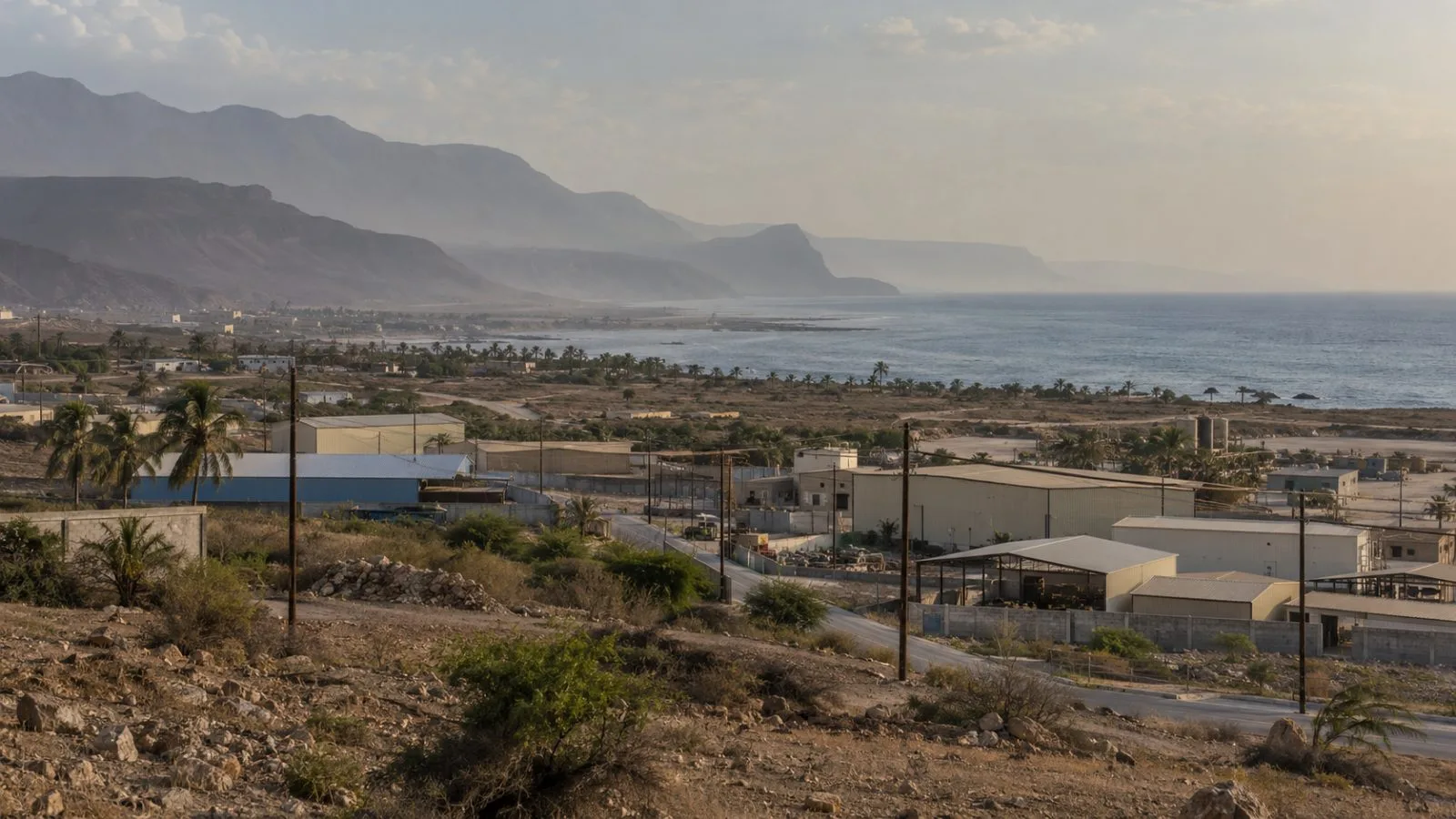 Industrial buildings and utility lines stand at the edge of Salalah, Oman (AI-generated image / EconoTimes)