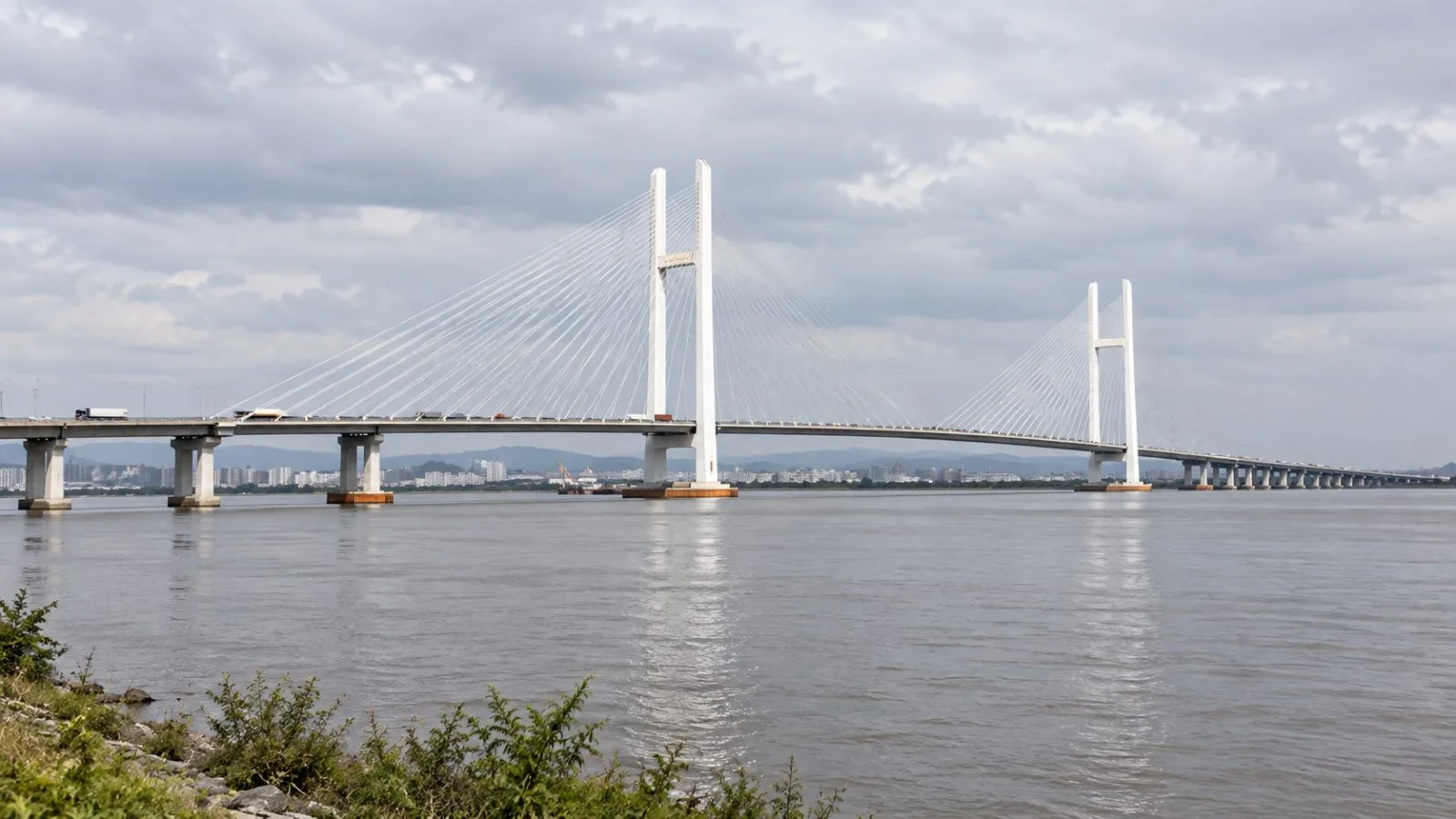 Road traffic crosses the New Yalu River Bridge over the Yalu River near Dandong, China. / EconoTimes.ai