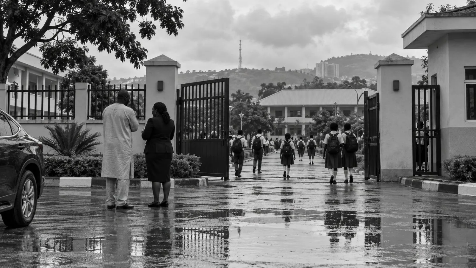 Parents and staff speak at a school gate in Abuja, Nigeria, on a cloudy morning. (AI-generated image / EconoTimes)