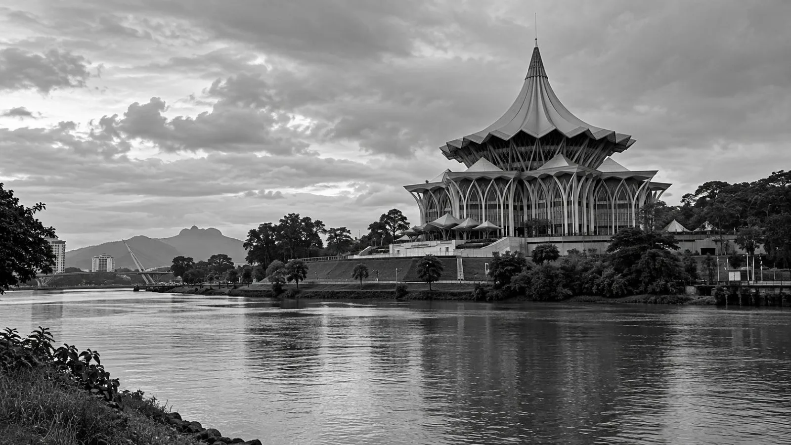 The Sarawak State Legislative Assembly building stands across the river in Kuching, Malaysia. / EconoTimes.ai (mono)