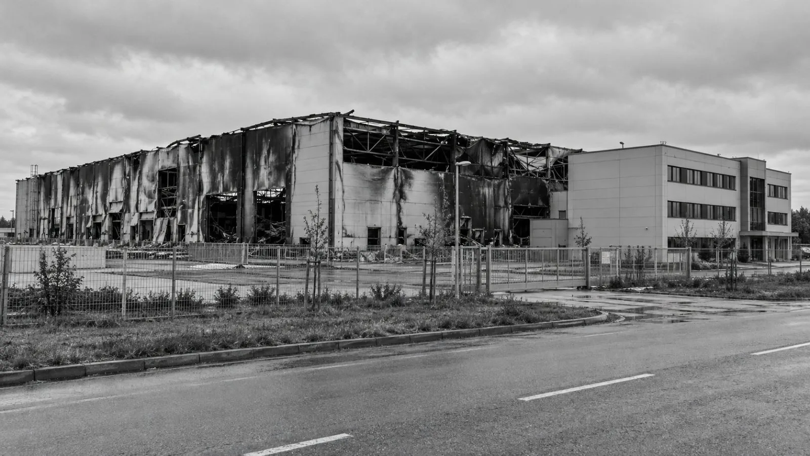 A fire-damaged storage hall stands beside an administrative building in Pardubice, Czech Republic. (AI-generated image / EconoTimes)