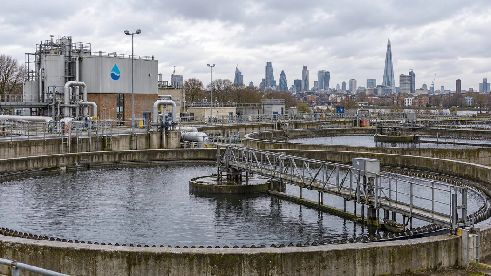 Settling tanks sit under overcast skies at a wastewater treatment works in London. / EconoTimes.ai