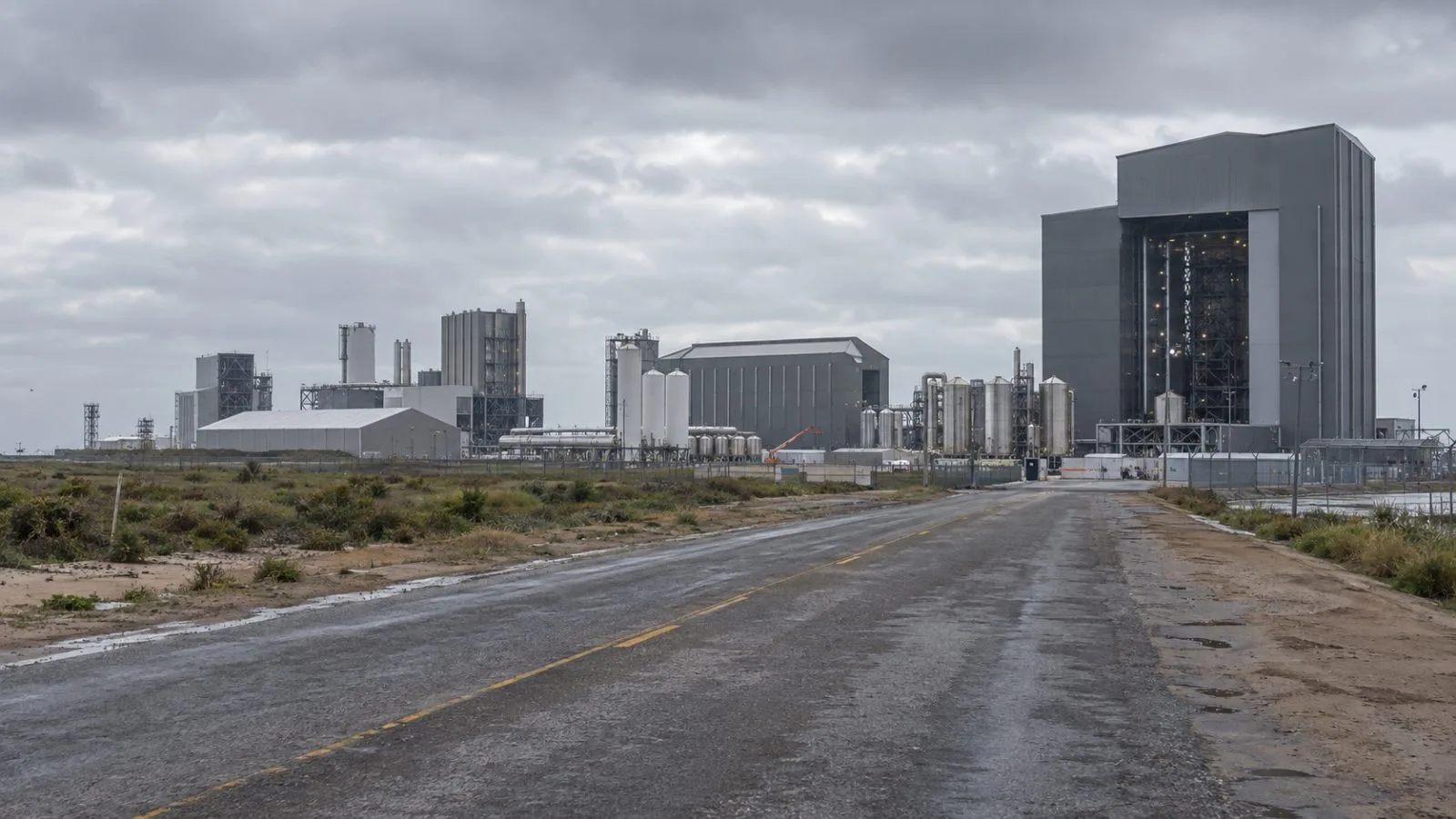 Facility buildings stand beyond an access road near Brownsville, Texas, in morning light. (AI-generated image / EconoTimes)