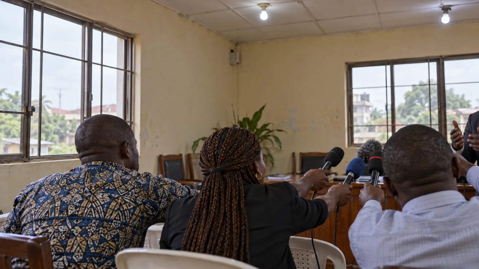 Reporters hold microphones at a press conference in Benin City, Nigeria. / EconoTimes.ai