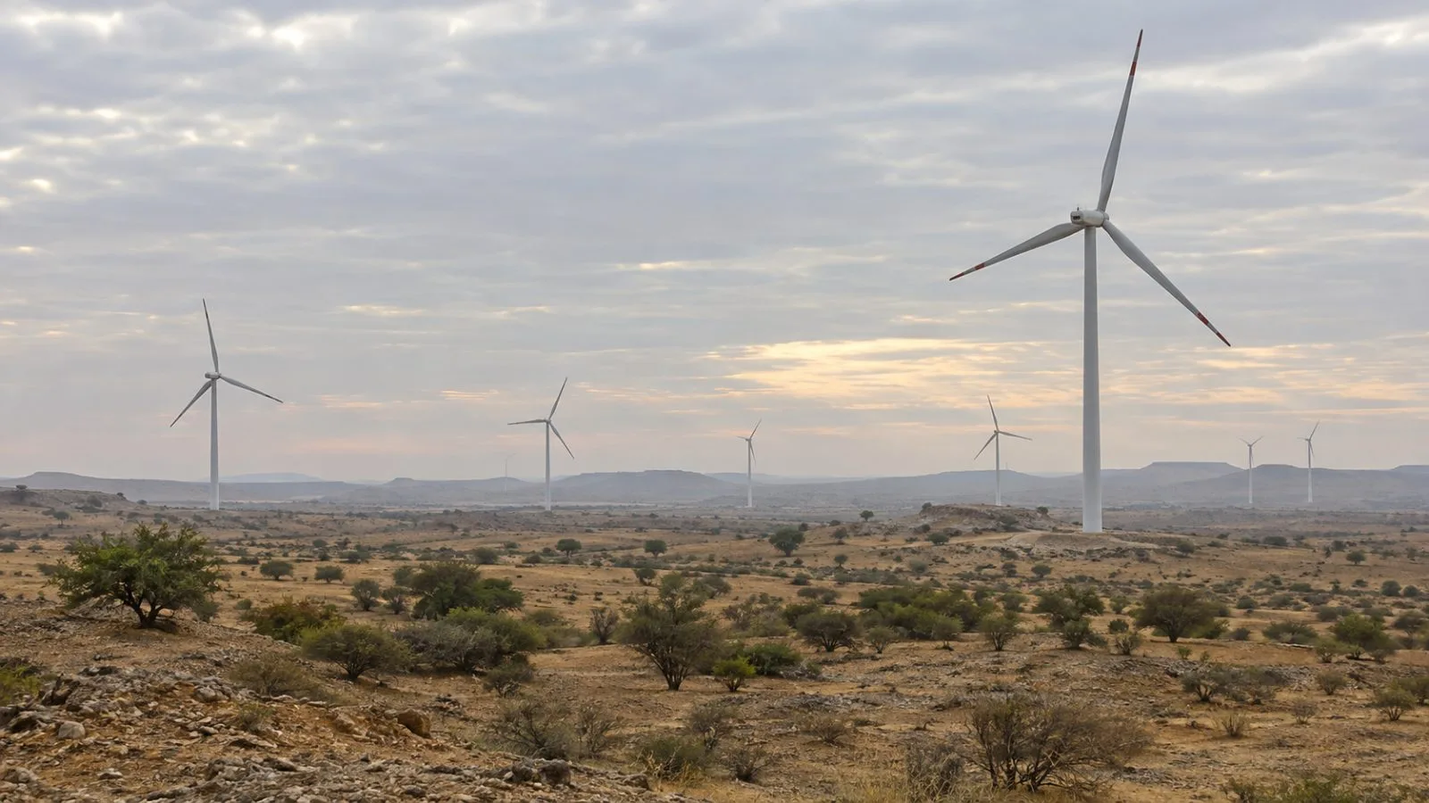 Wind turbines turn above dry scrubland near Jaisalmer, Rajasthan, India / EconoTimes.ai