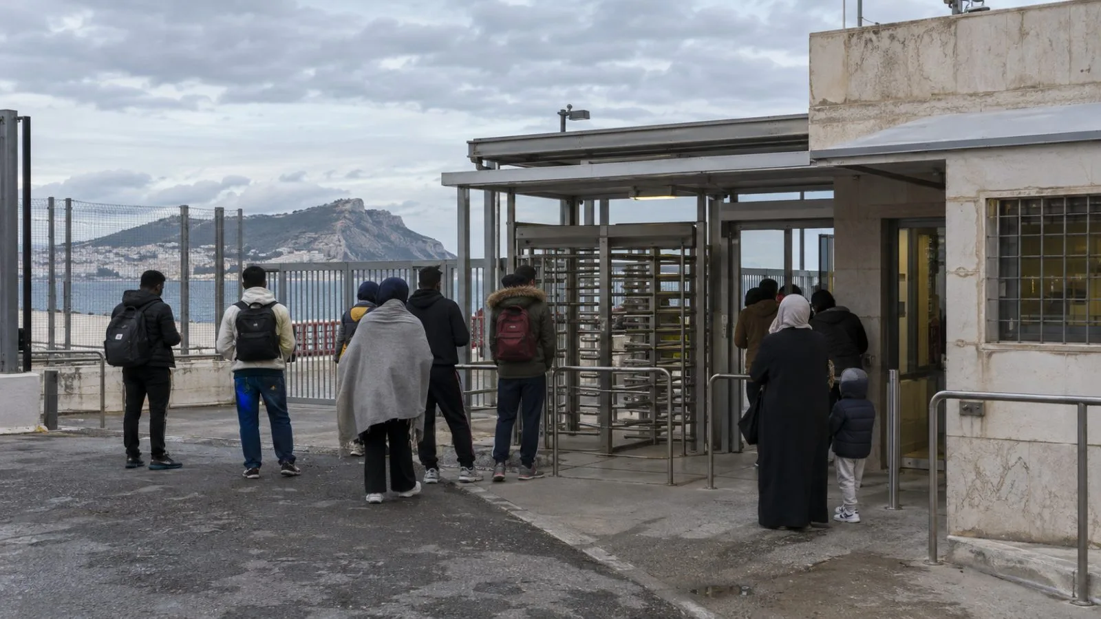 People wait outside a migrant reception center in Ceuta, Spain. (AI-generated image / EconoTimes)