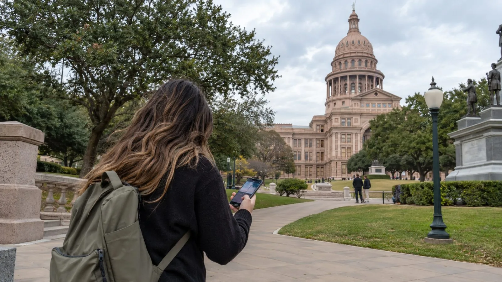 A passerby checks a smartphone outside the Texas State Capitol in Austin, Texas. (AI-generated image / EconoTimes)