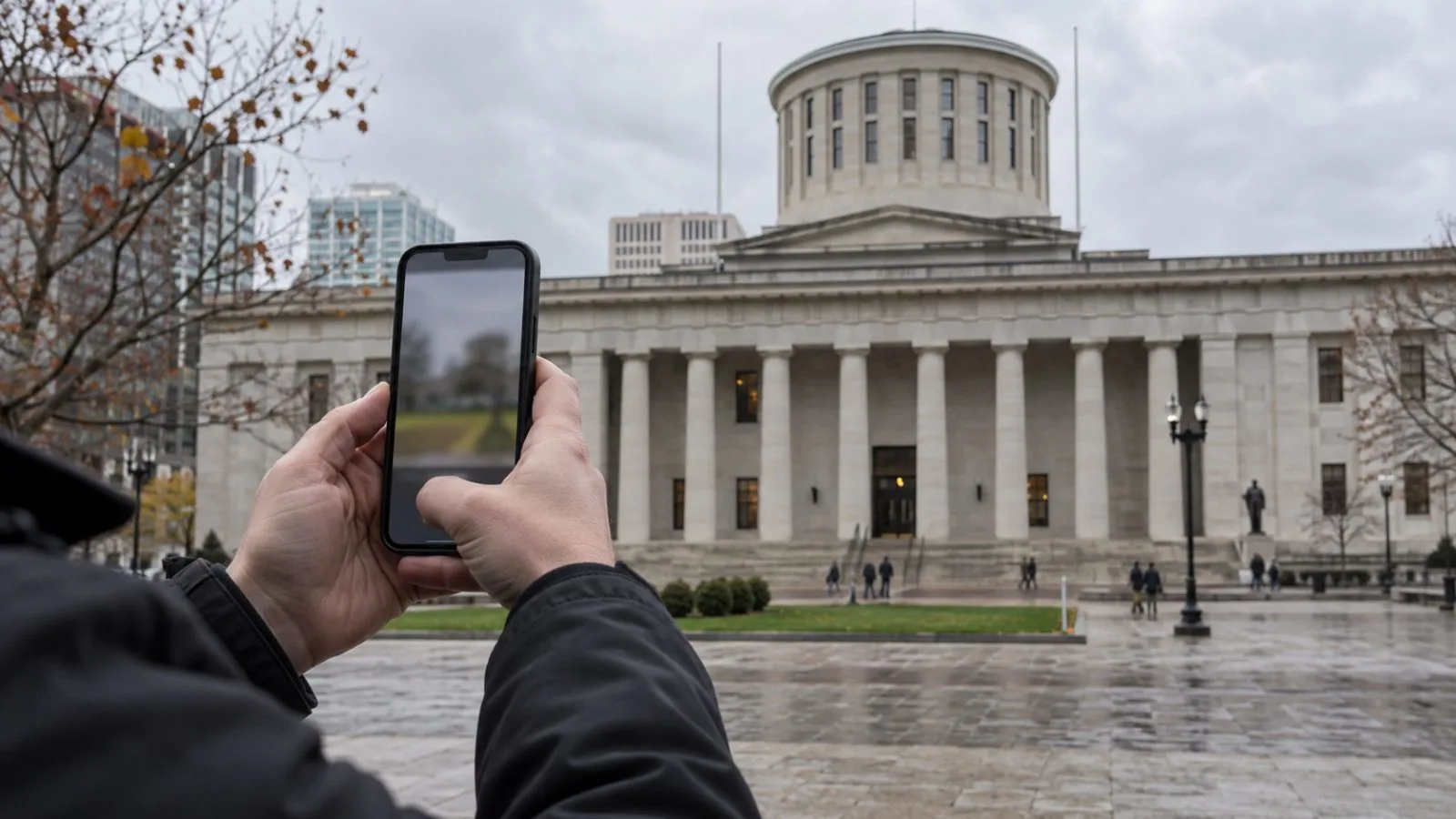 A passerby watches a political video on a smartphone outside the Ohio Statehouse in Columbus. / EconoTimes.ai