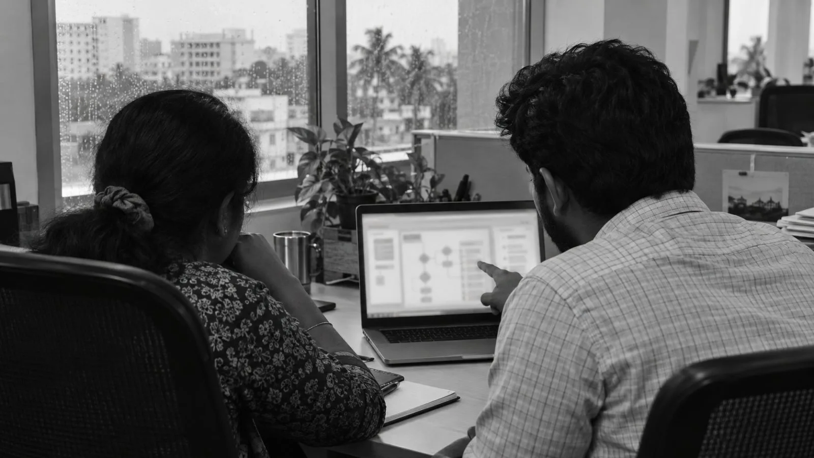 Office workers review a software workflow on a laptop in Chennai, India. (AI-generated image / EconoTimes)
