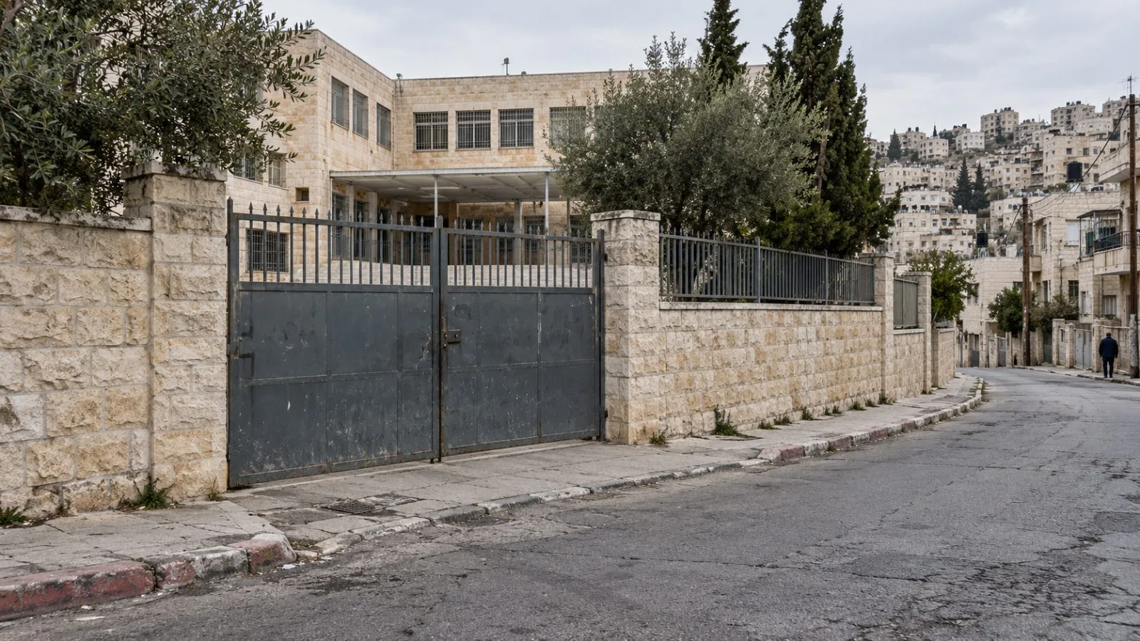 A closed school gate stands along a quiet street in Hebron, West Bank (AI-generated image / EconoTimes)